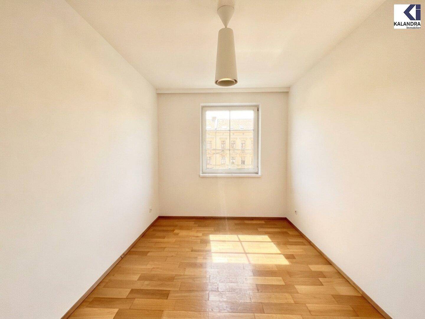 Geräumiges Zimmer mit Parkettboden und großem Fenster, ideal als Schlaf- oder Arbeitszimmer.