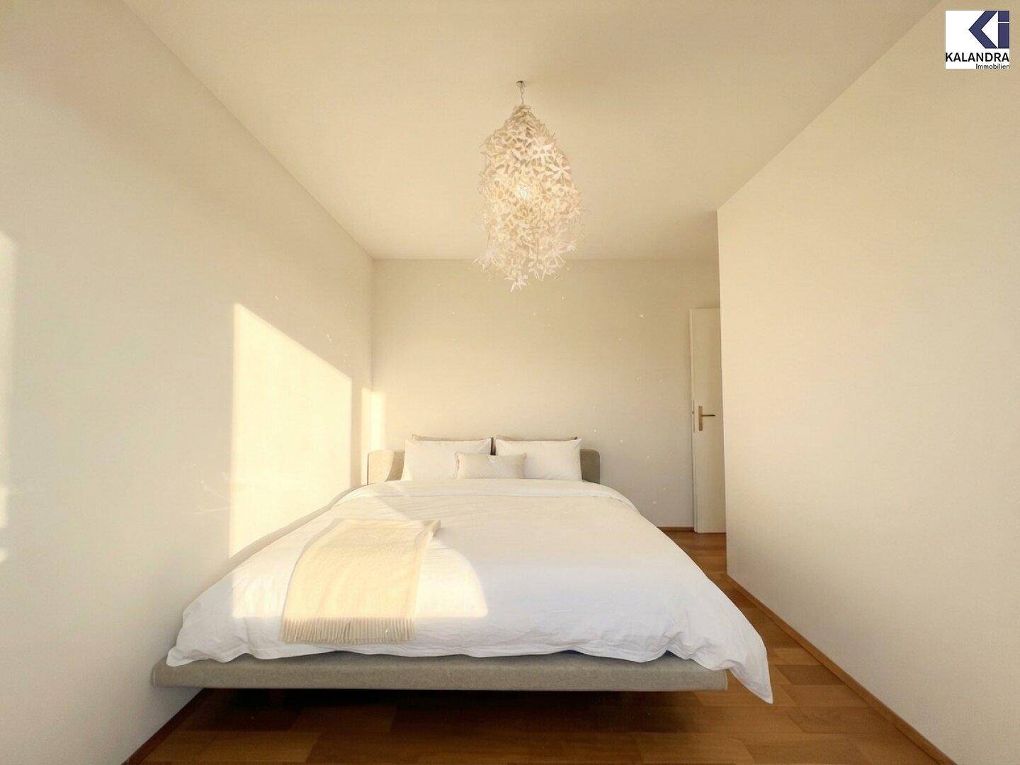 Helles Schlafzimmer mit Parkettboden und modernem Bettgestell.