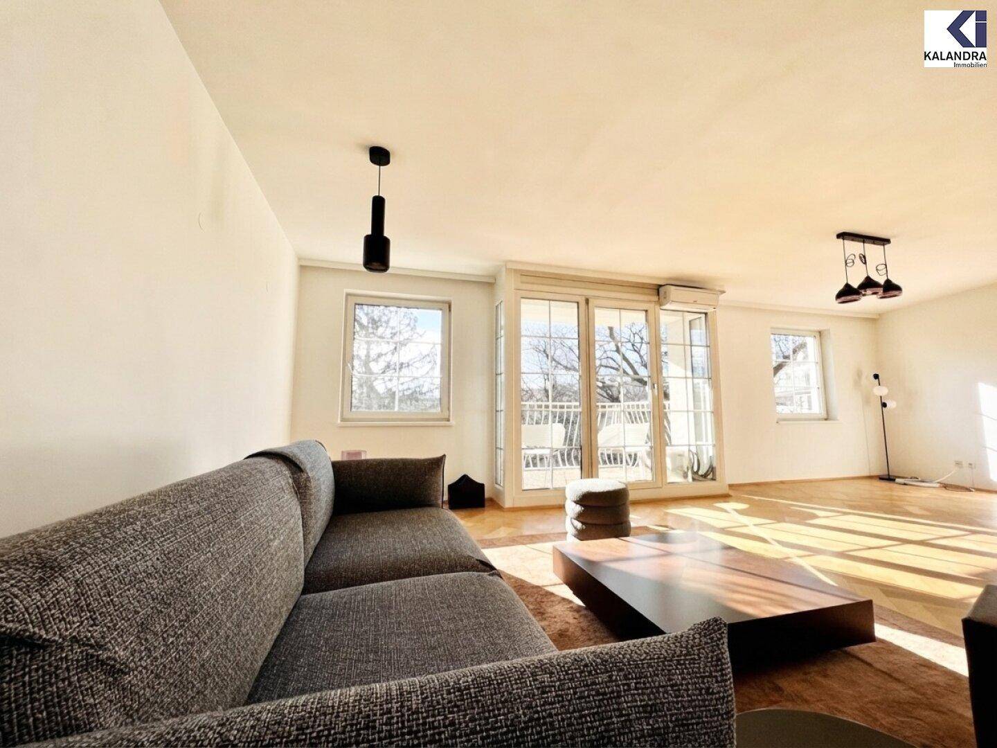 Lichtdurchflutetes Wohnzimmer mit Parkettboden und Blick auf den Außenbereich.