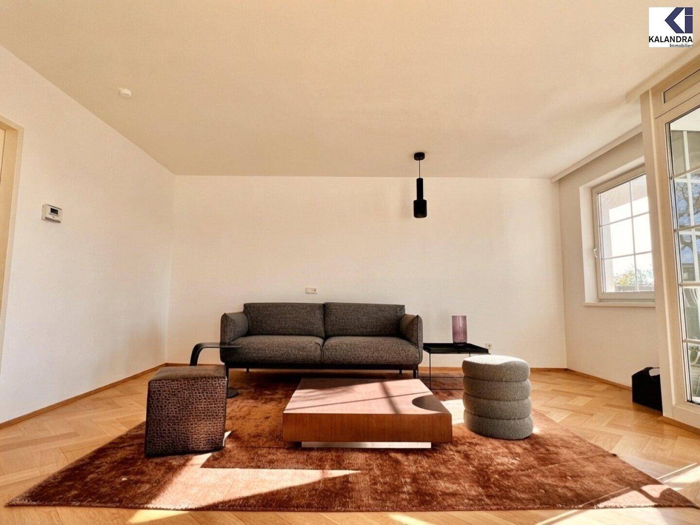 Helles Wohnzimmer mit Parkettboden, gemütlicher Couch und großem Fenster.