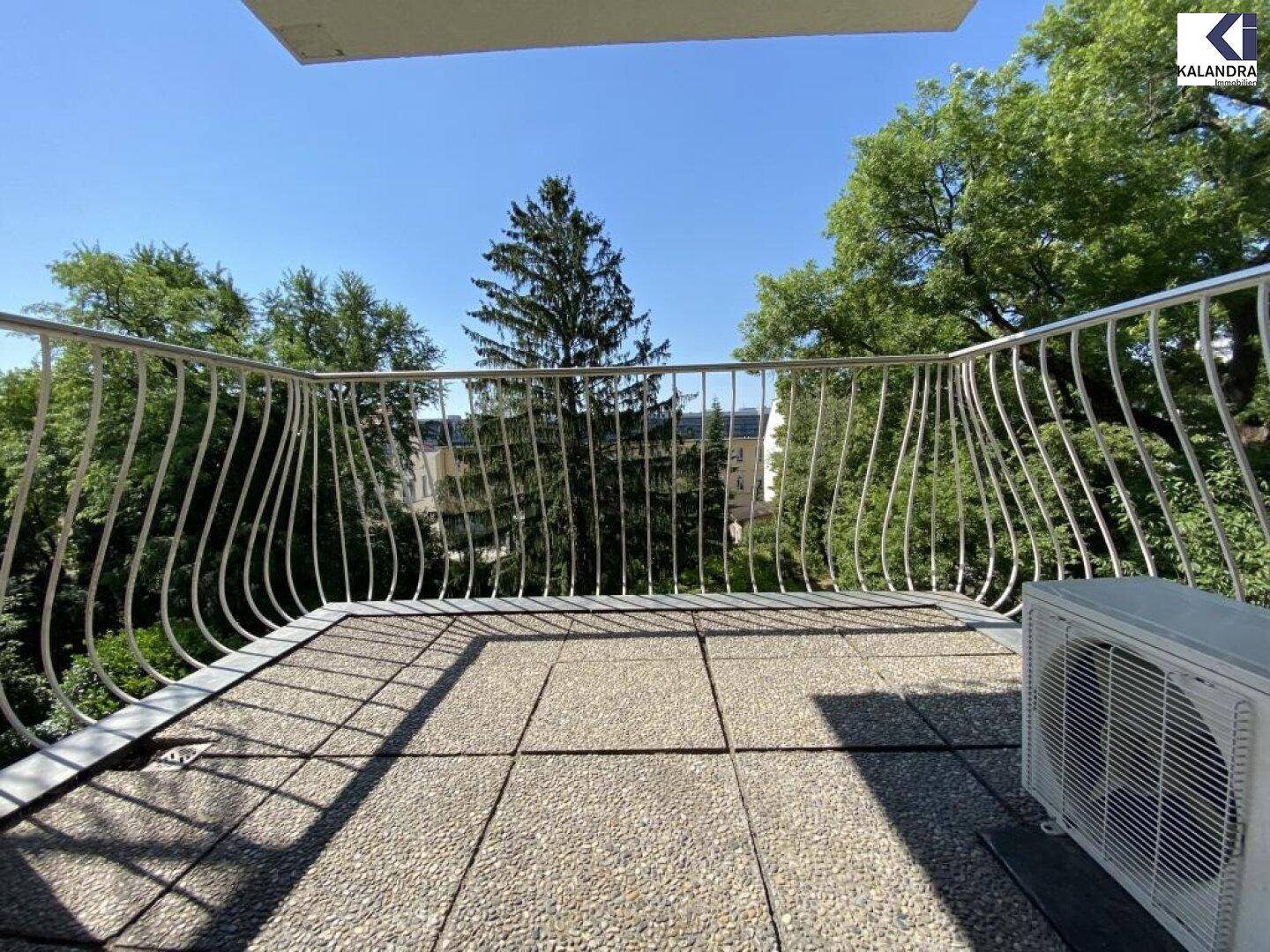 Balkon mit Fliesenboden und Klimaanlage, bietet einen Blick ins Grüne.