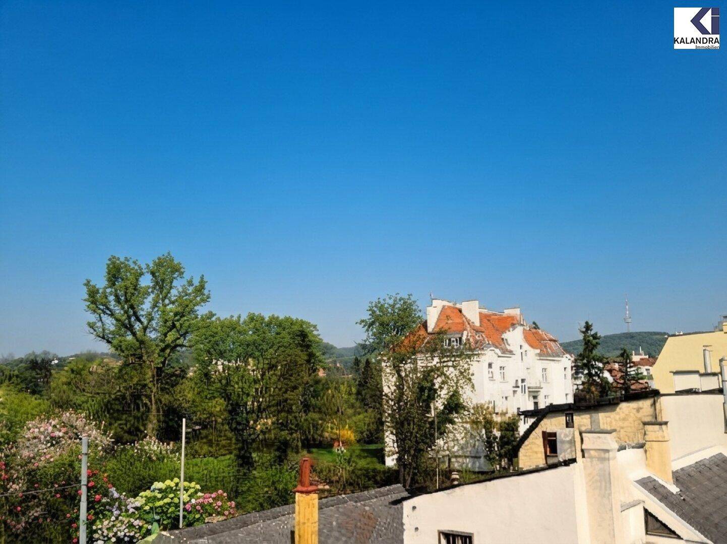 Panoramablick über die Stadt und grüne Hügel unter blauem Himmel.