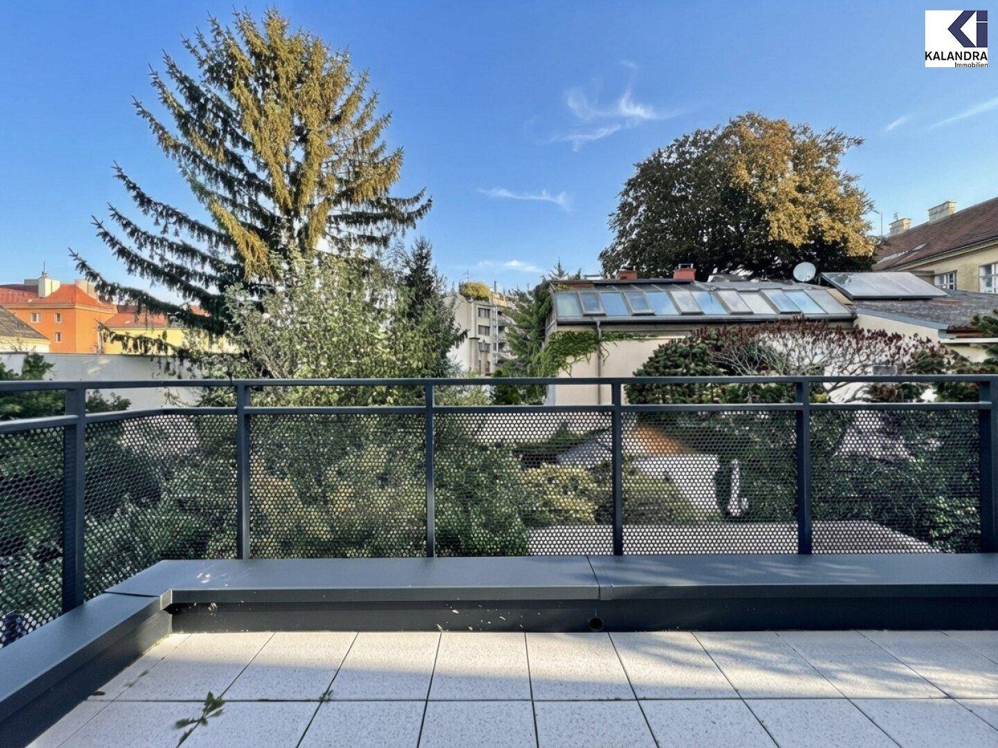 Weitläufiger Blick von der Terrasse auf grüne Bäume und die umliegende Stadtbebauung.