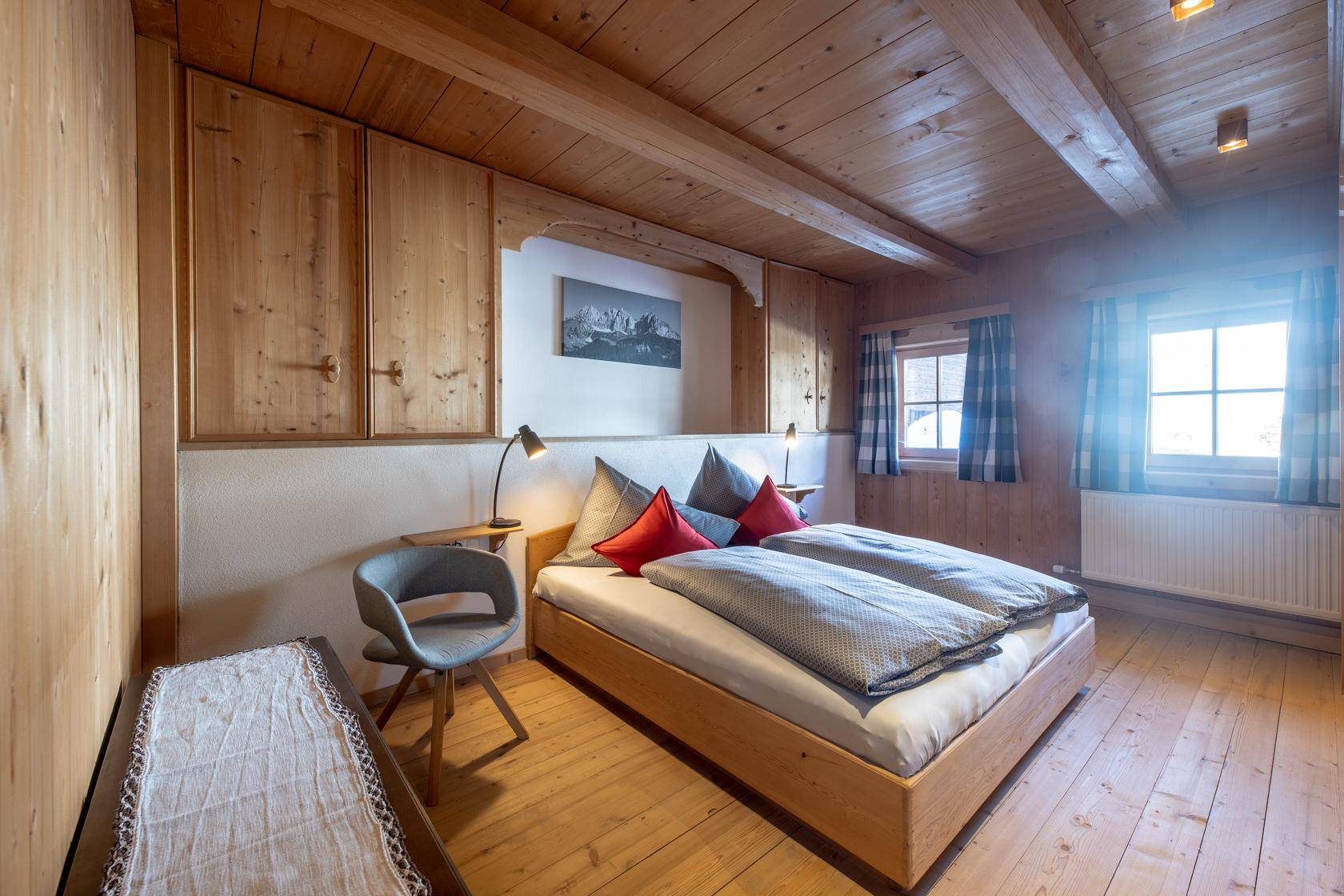 Helles Schlafzimmer mit Holzboden, Holzbalkendecke und traditionellen Holzmöbeln.