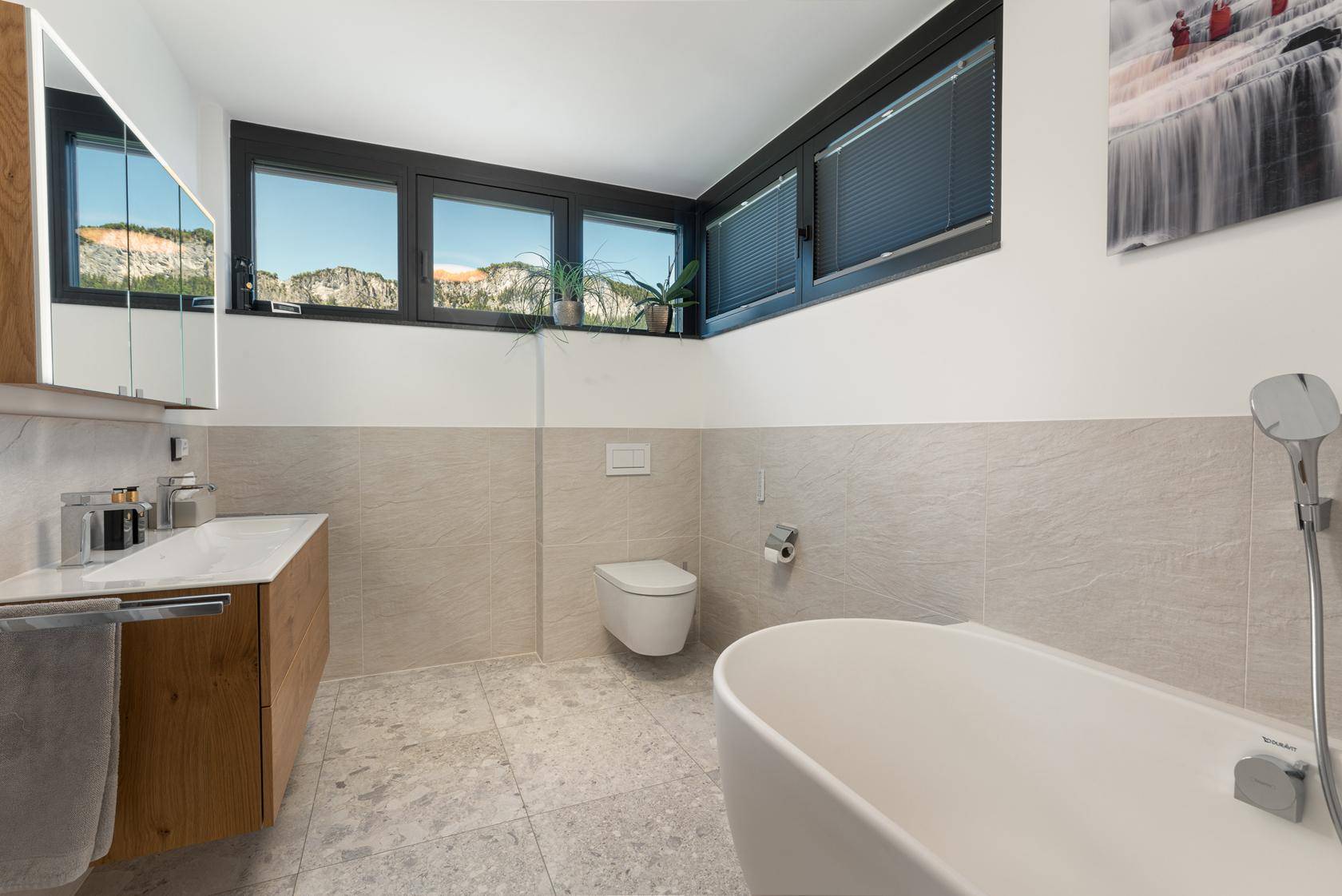 Helles Badezimmer mit freistehender Badewanne, Doppelwaschbecken und Bergblick.