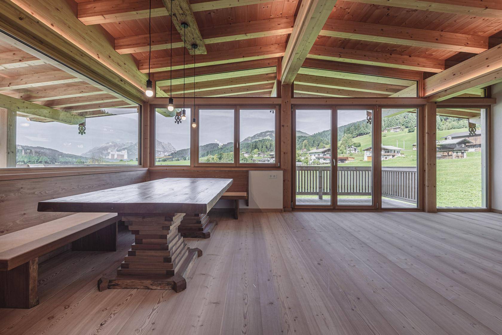 Offener Wohnbereich mit Holzbalkendecke, großem Esstisch und Panoramablick.