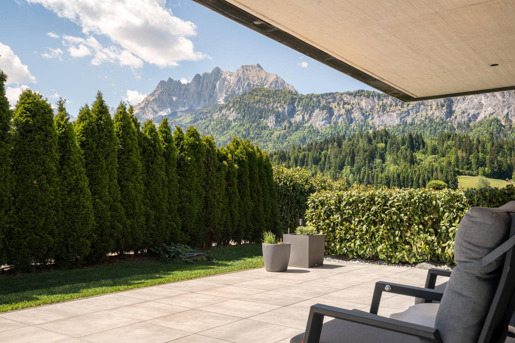 Sonnige Terrasse mit bequemen Stühlen und weitem Blick auf die majestätischen Berge.