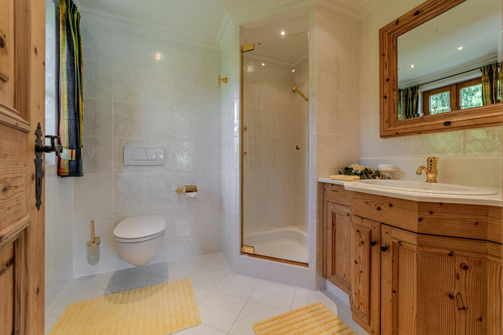 Helles Badezimmer mit Duschkabine, Wand-WC und Holzwaschtisch im traditionellen Stil.
