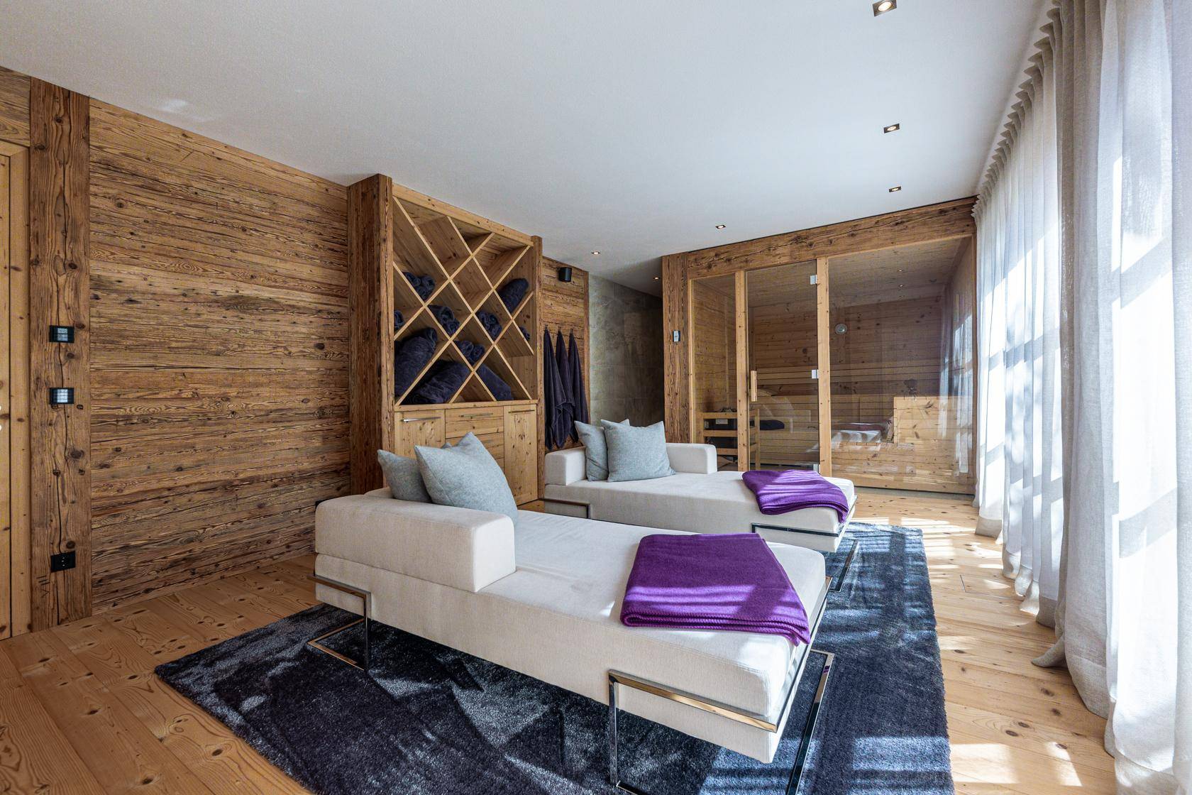 Entspannungsbereich mit Liegen, Holzwänden und einer sichtbaren Sauna für Wellness.