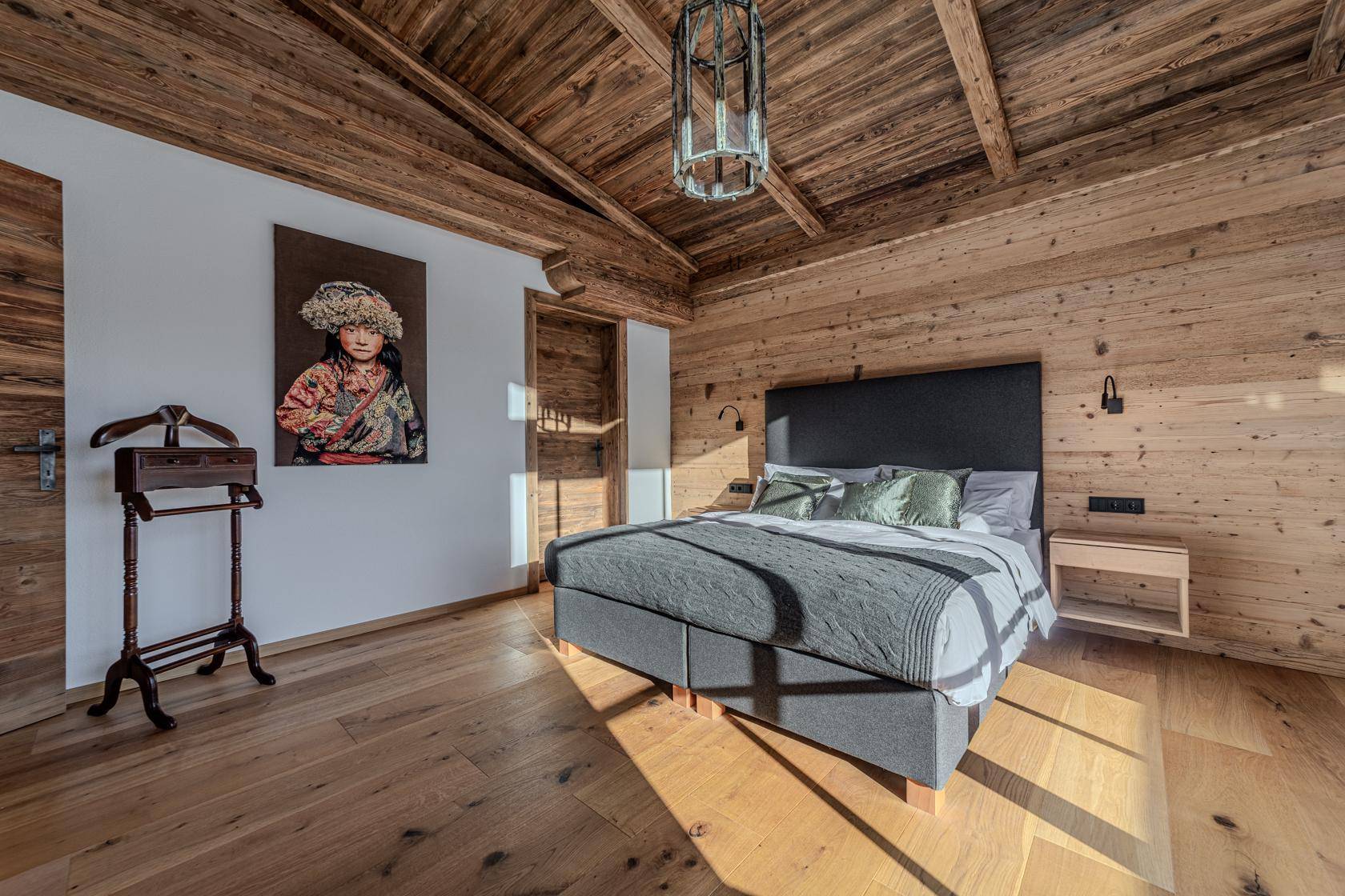 Rustikales Schlafzimmer mit Holzbalkendecke, Holzwänden und modernem Bett.