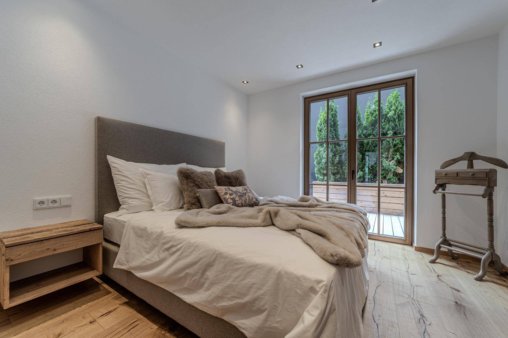 Helles Schlafzimmer mit Holzboden und Zugang zu einer Terrasse oder einem Balkon.