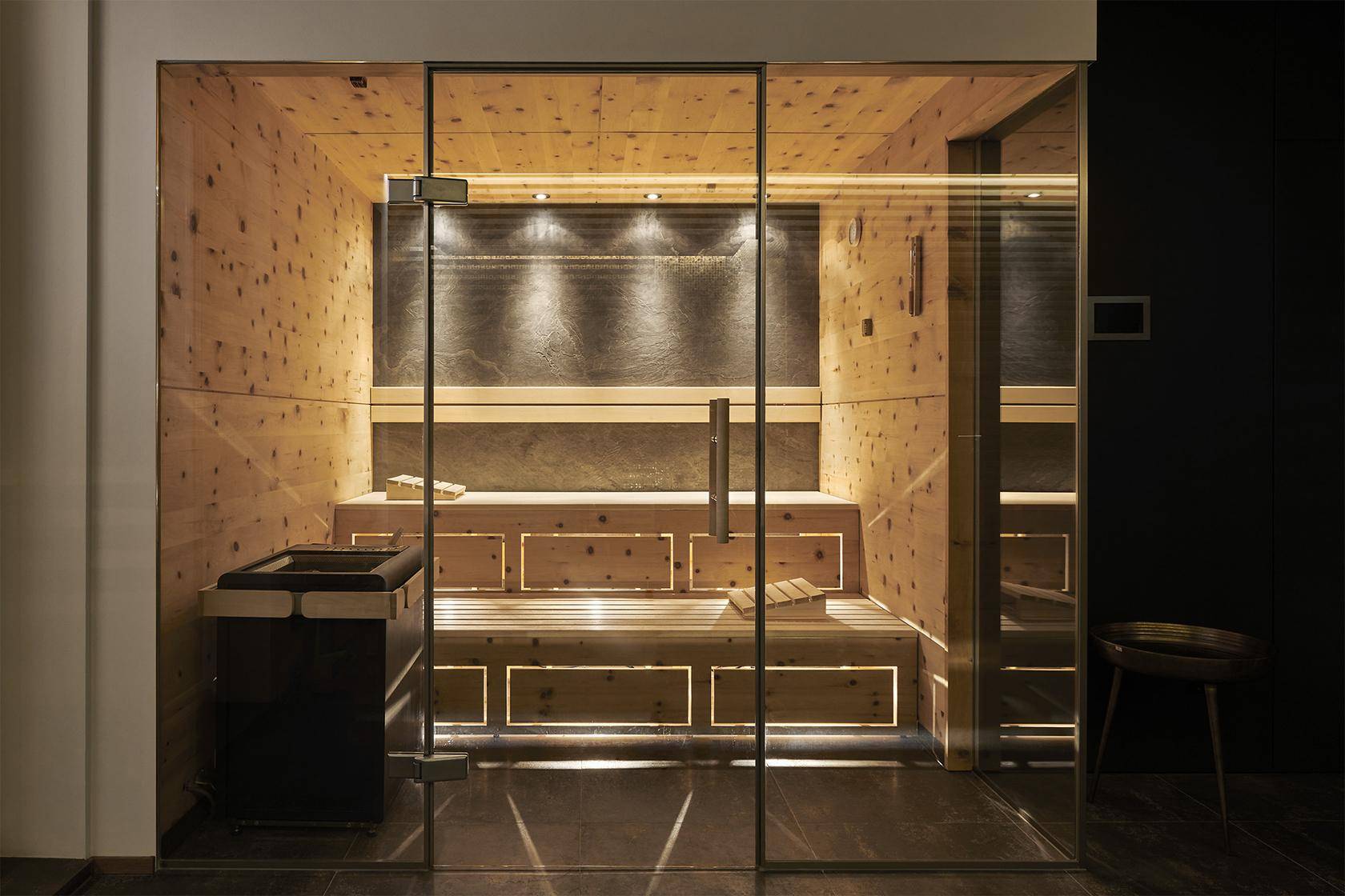 Moderne Sauna mit Holzbänken, Glasfront und stimmungsvoller Beleuchtung für pure Entspannung.