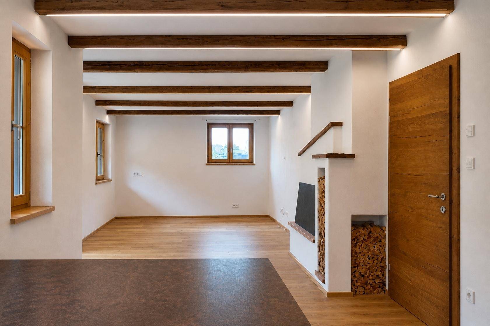 Heller Wohnraum mit Holzbalken, Parkettboden und einem dekorativen Holzstapelbereich, der Gemütlichkeit ausstrahlt.