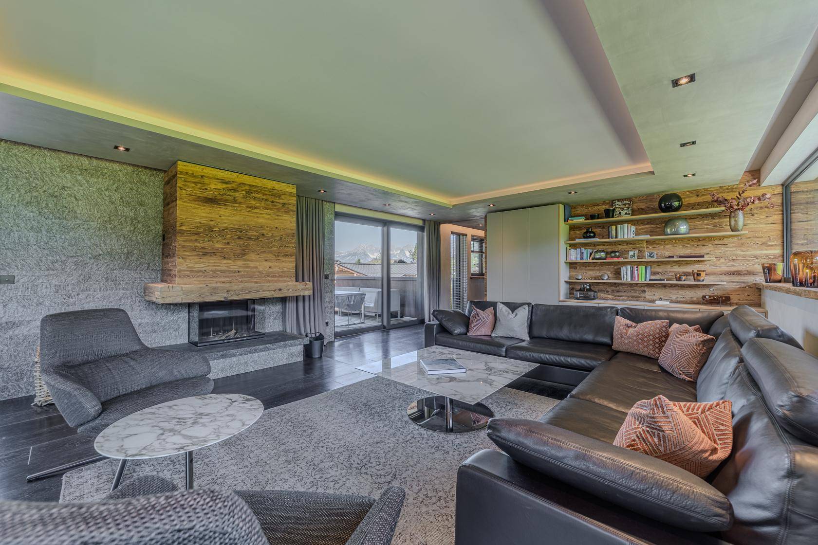 Elegantes Wohnzimmer mit Kamin, dunklem Holzboden und großen Fenstern mit Bergblick.