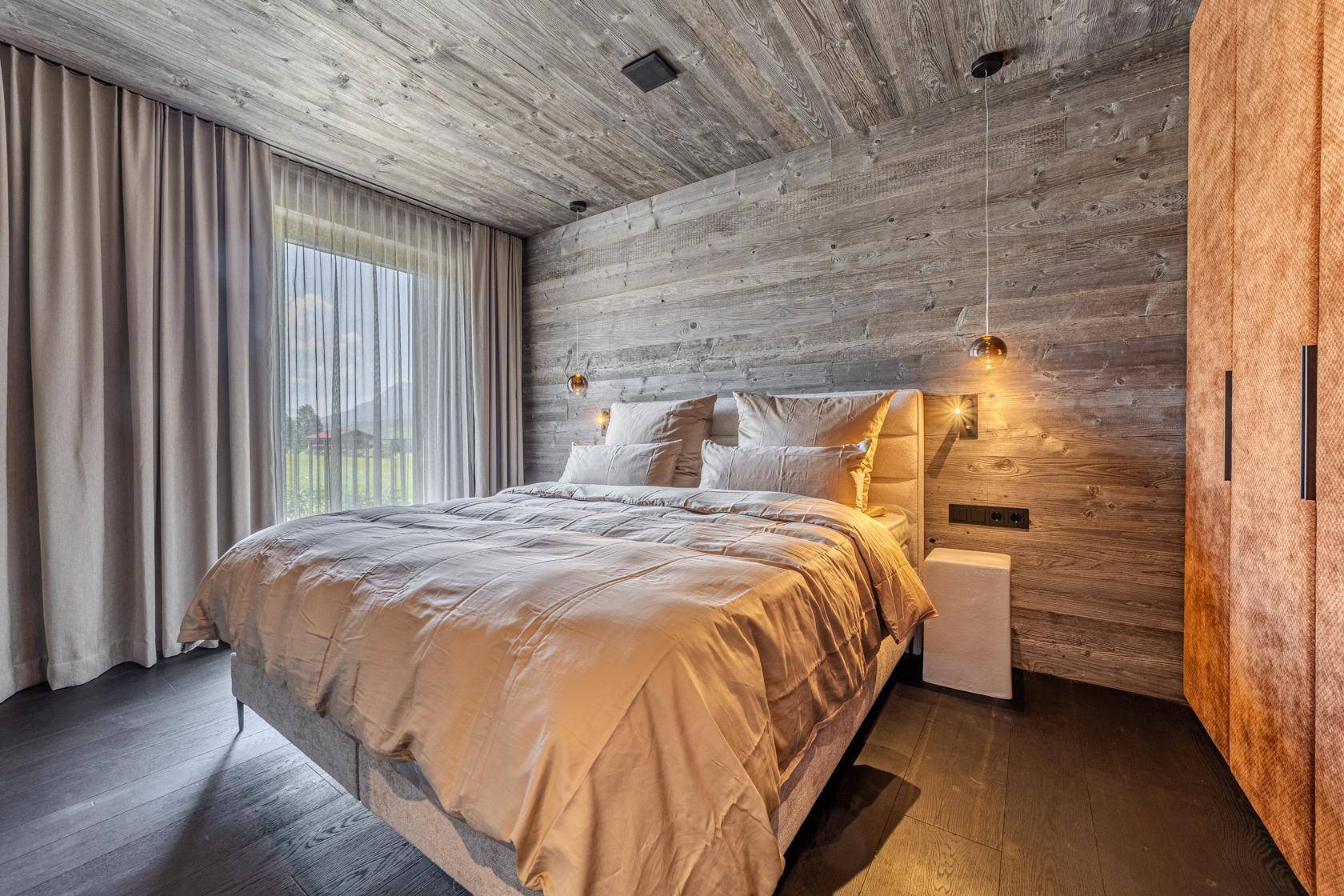Komfortables Schlafzimmer mit Holzwänden, großem Bett und integrierten Kleiderschränken.