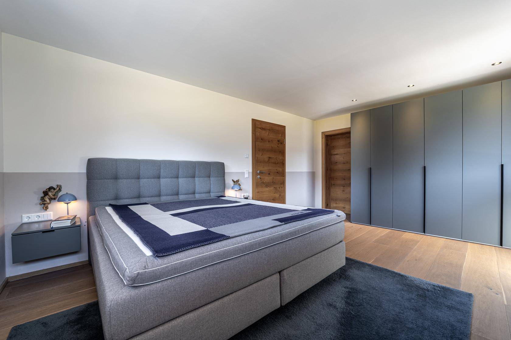 Gemütliches Schlafzimmer mit großem Bett, modernen Einbauschränken und Holzboden.