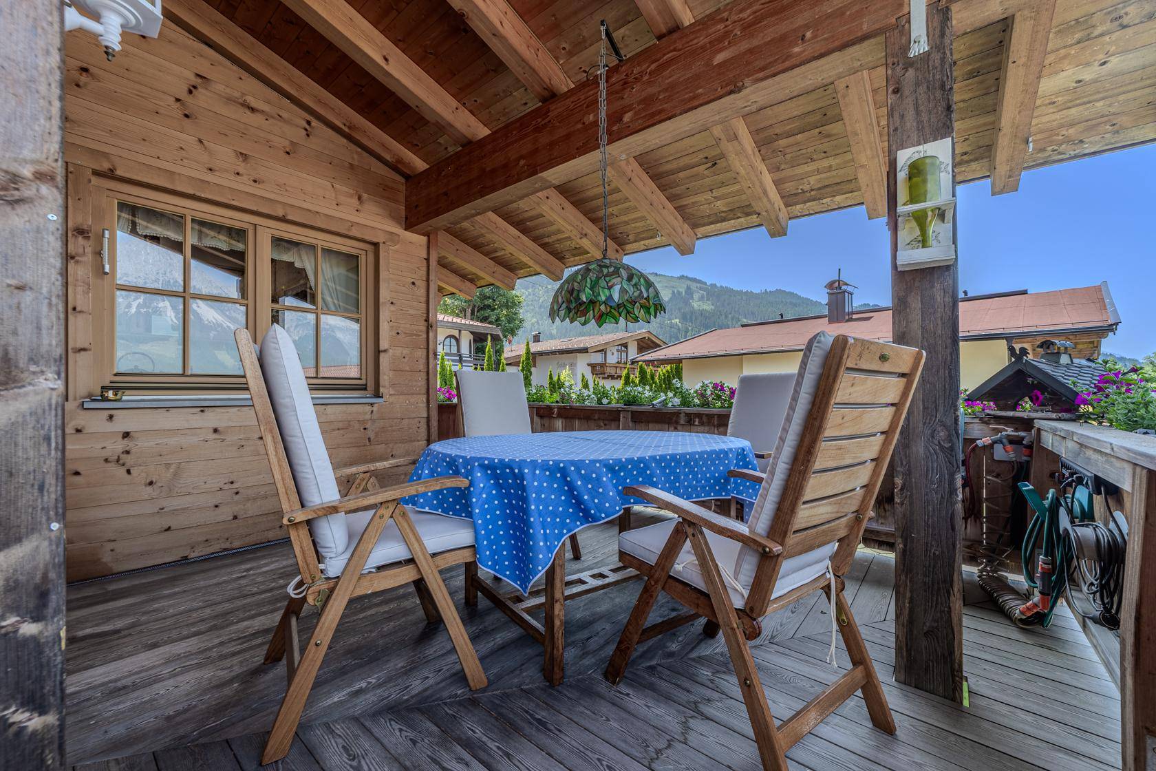 Überdachter Holzbalkon mit Sitzgelegenheiten und Blick auf die umliegende Berglandschaft.