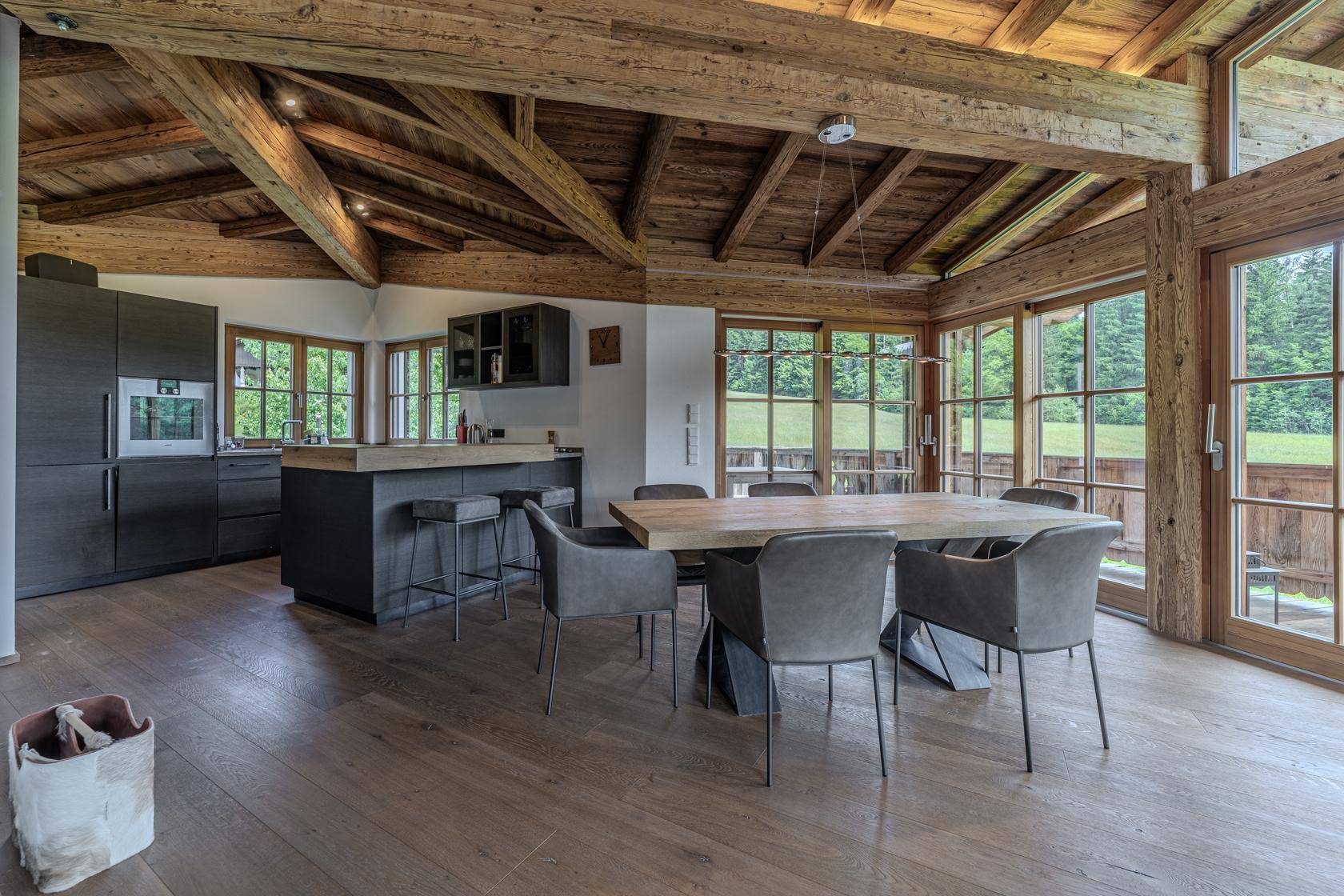 Moderne Küche mit dunklen Schränken, Holztheke und Essbereich mit Balkonzugang.