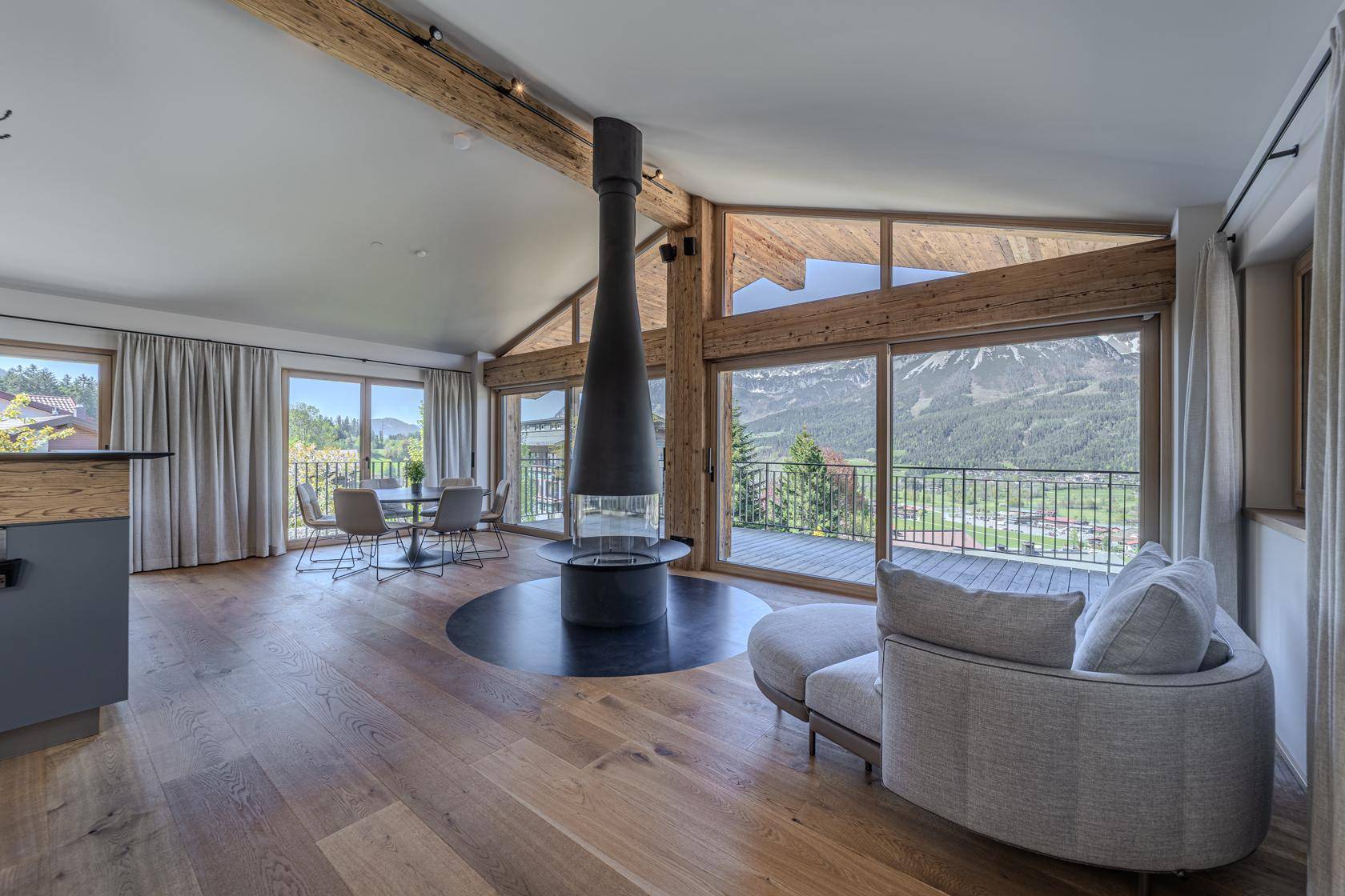 Geräumiger Wohnbereich mit freistehendem Kamin, Holzbalken und Zugang zur Terrasse.