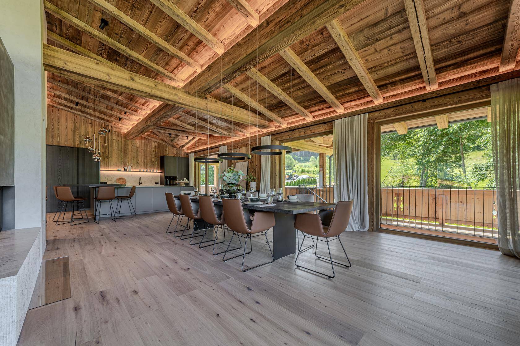 Geräumiger Wohn-Essbereich mit Holzbalkendecke, Esstisch und Zugang zum Außenbereich.