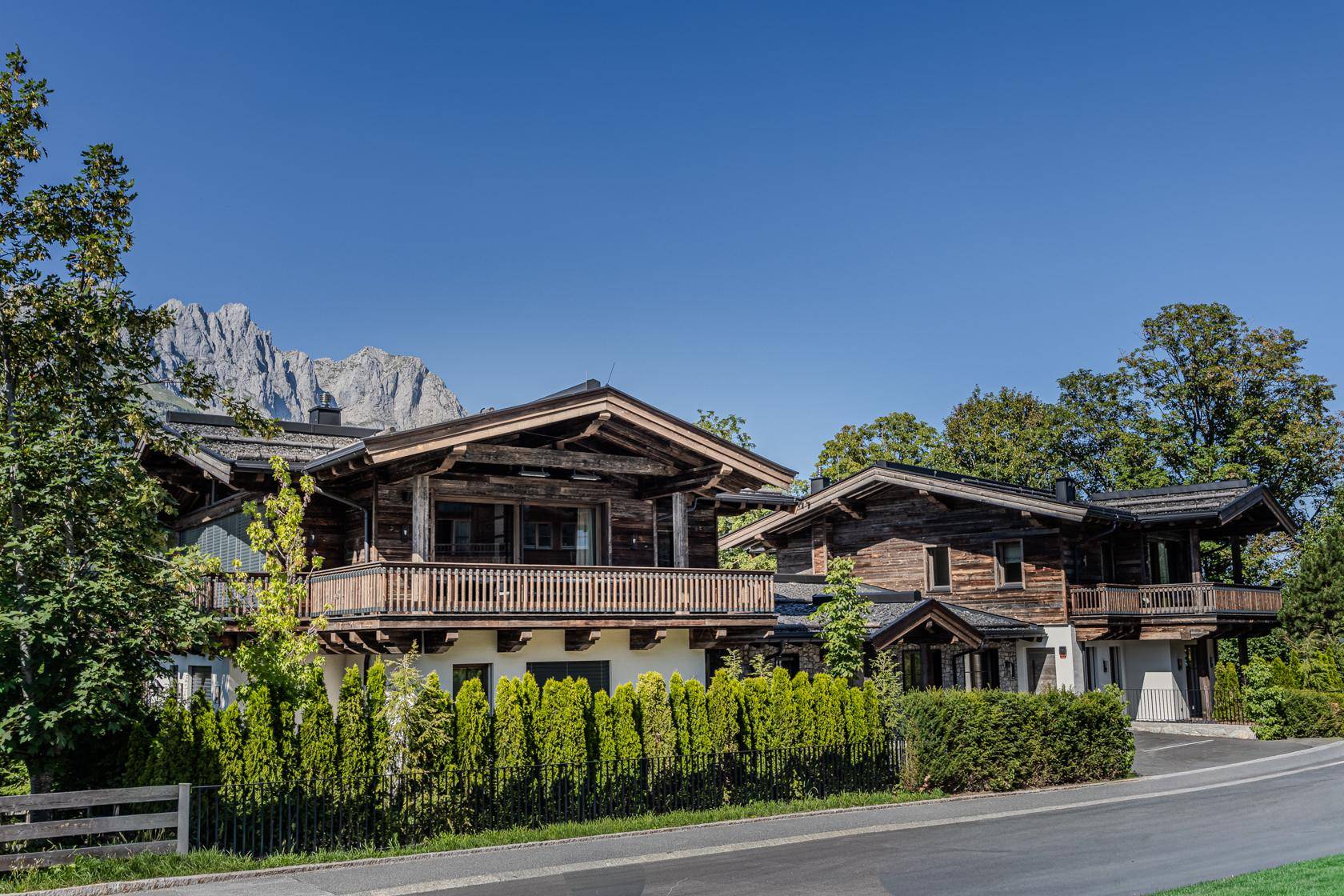 Charmantes Chalet-Anwesen mit Holzbalkonen, umgeben von Grün und mit Bergblick.