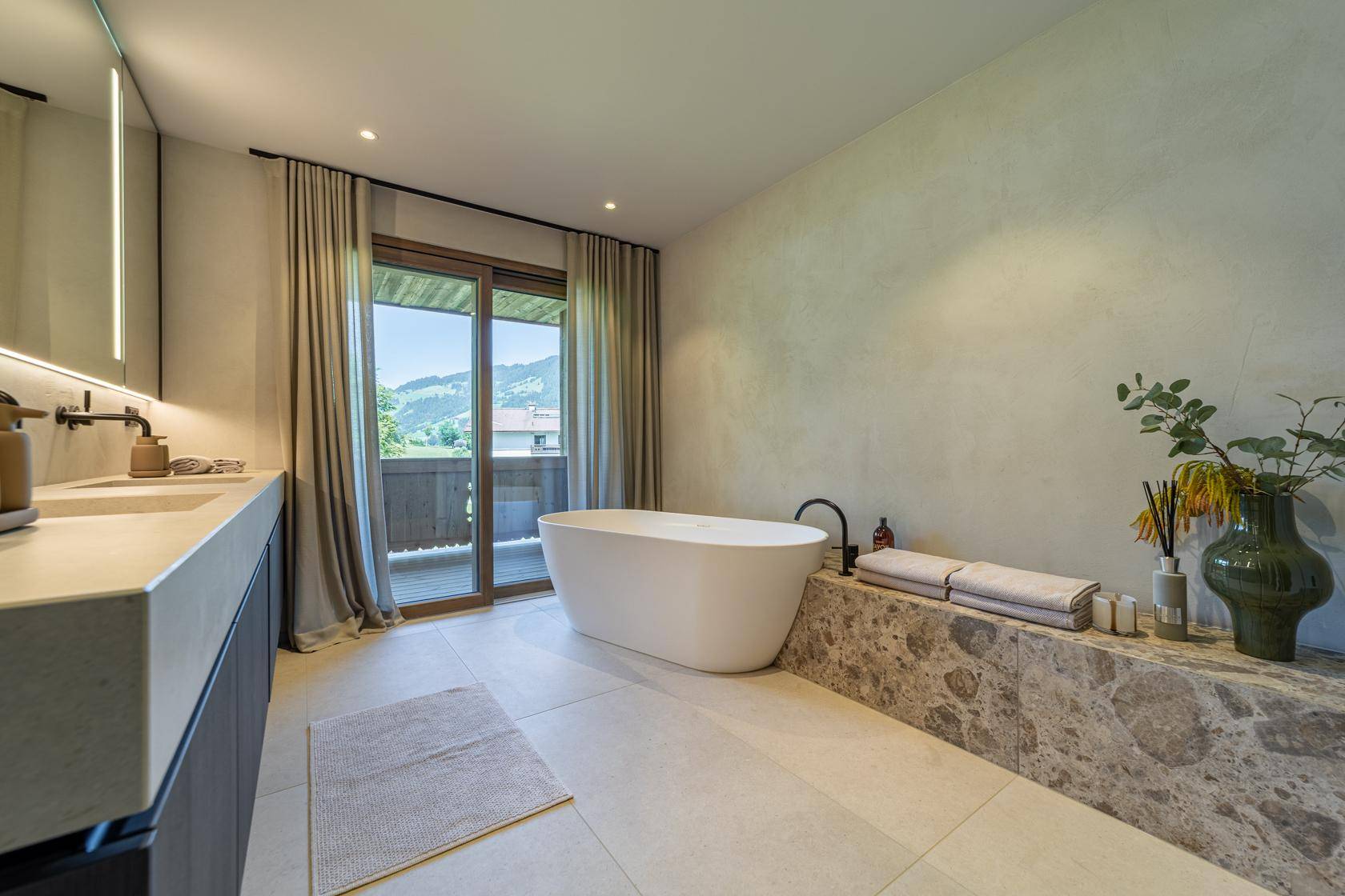 Modernes Badezimmer mit freistehender Badewanne, Doppelwaschbecken und Balkonzugang.