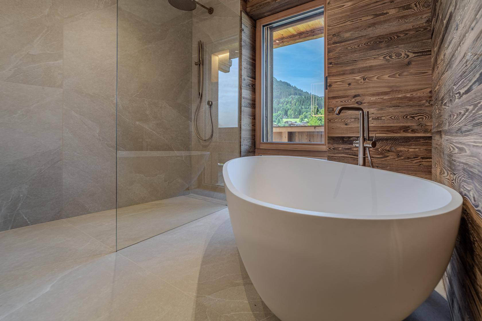 Modernes Badezimmer mit freistehender Badewanne, begehbarer Dusche und Bergblick.