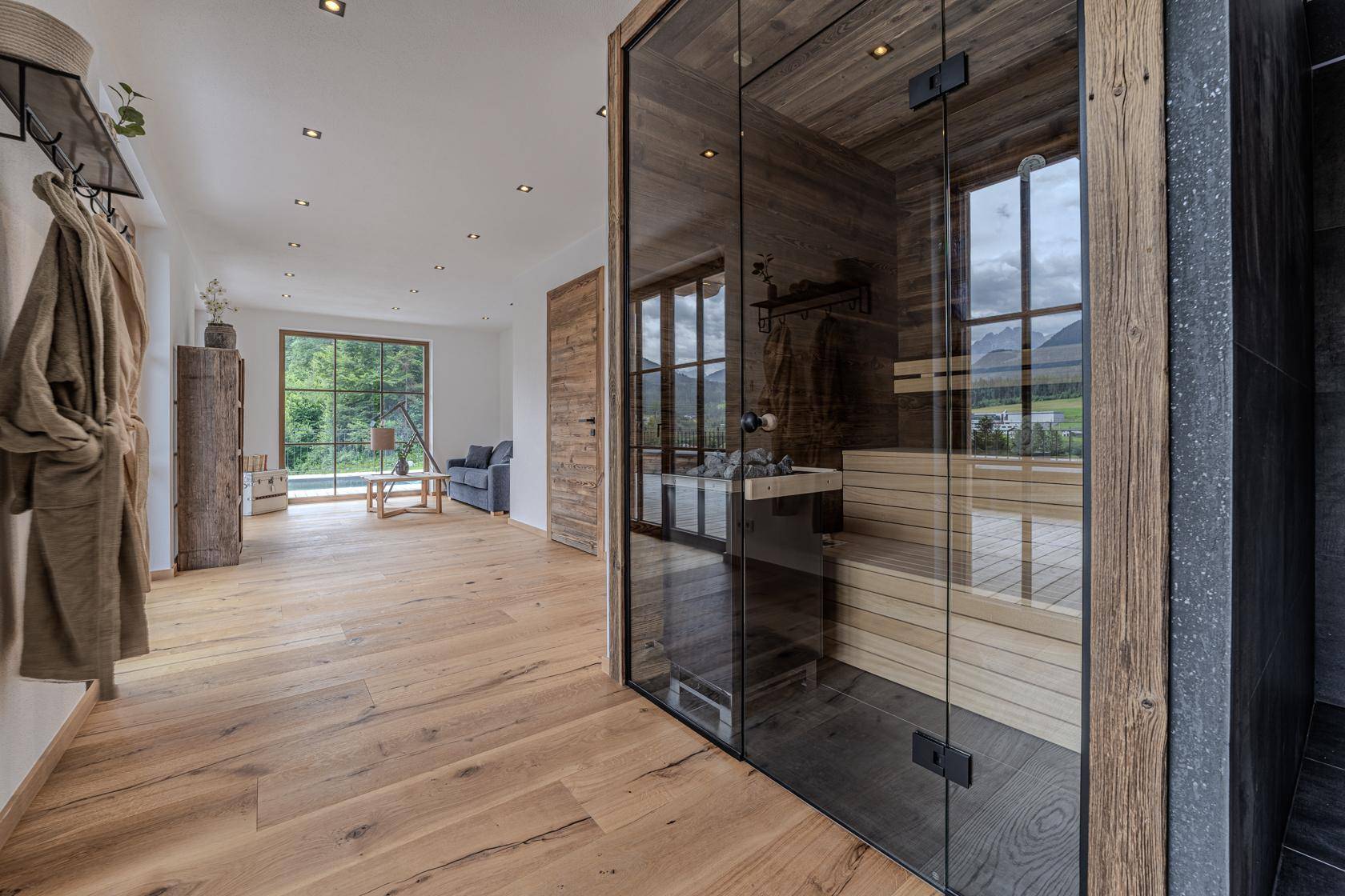 Heller Flurbereich mit Holzboden und einer modernen Sauna mit Glasfront.