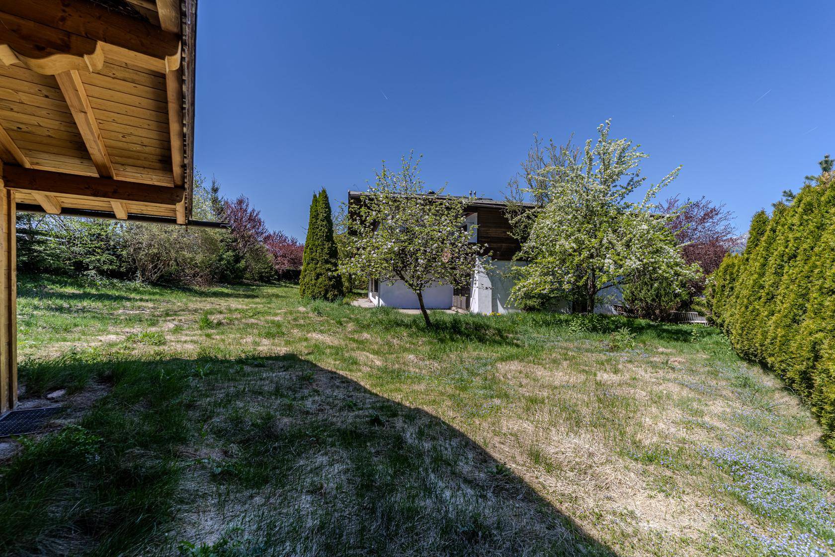 Weitläufiger Gartenbereich mit Blick auf das Haus und umliegende grüne Landschaft.