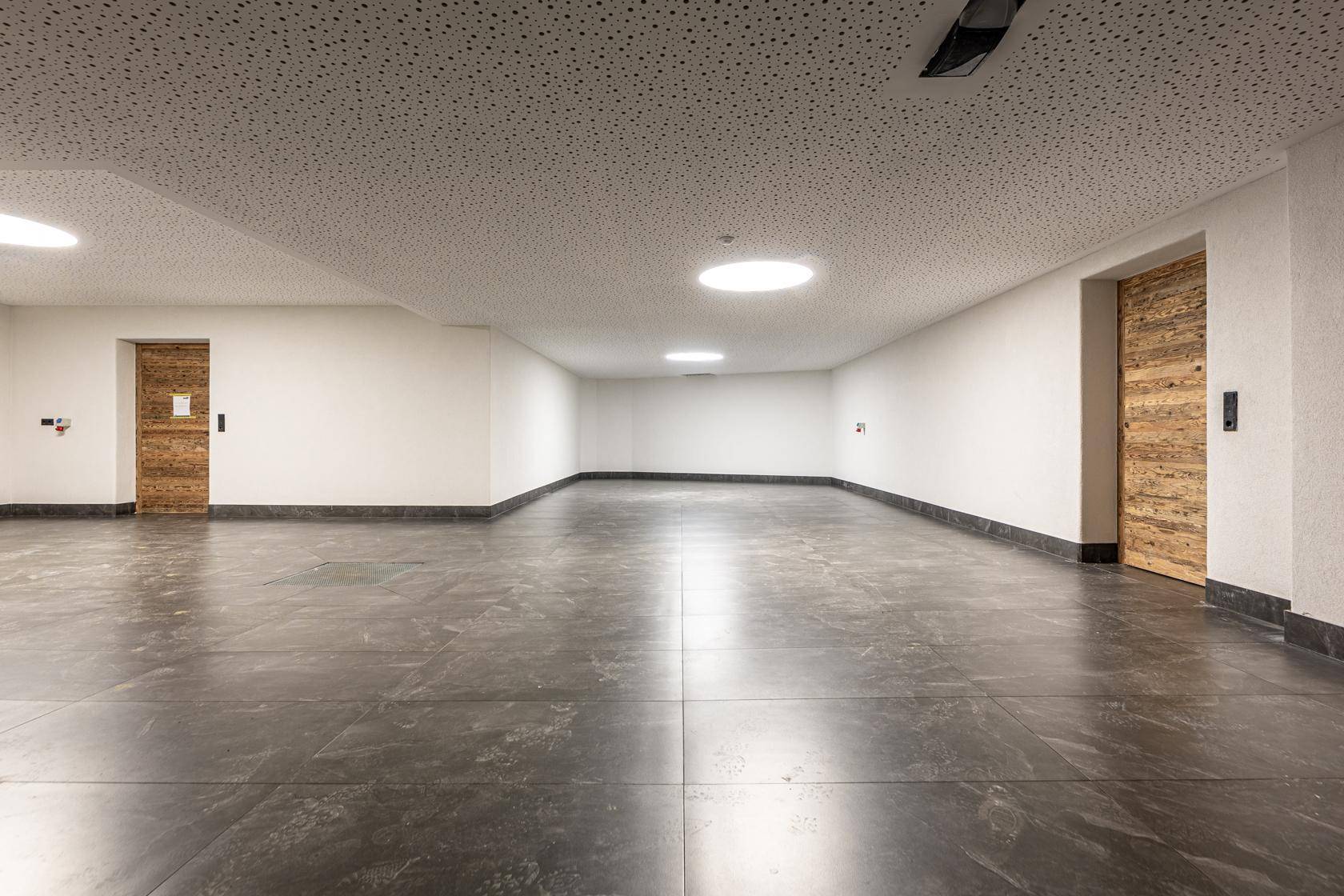 Geräumige Tiefgarage mit Fliesenboden und Zugang zu den Wohneinheiten.