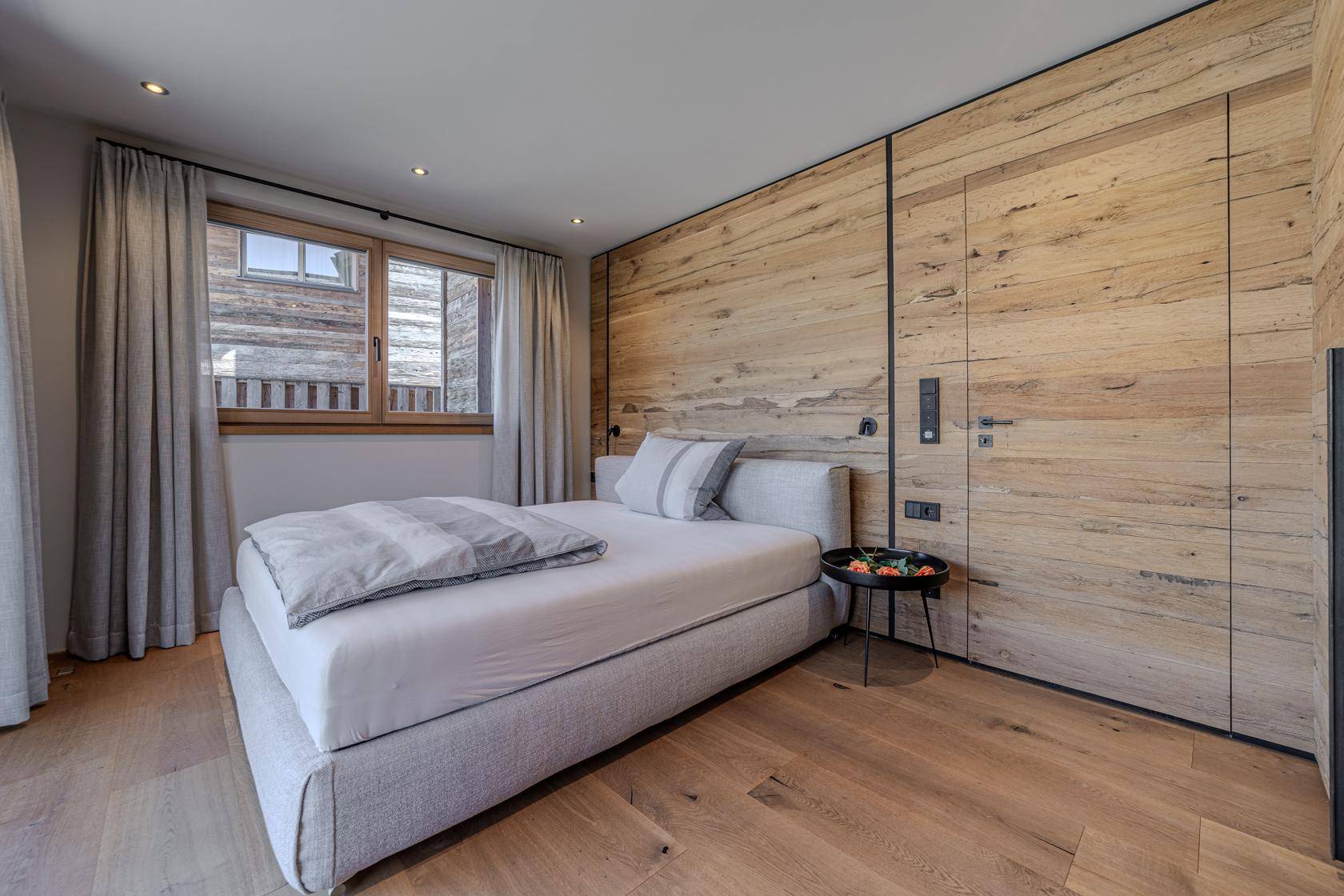 Helles Schlafzimmer mit Holzwänden, großem Fenster und modernem Design.