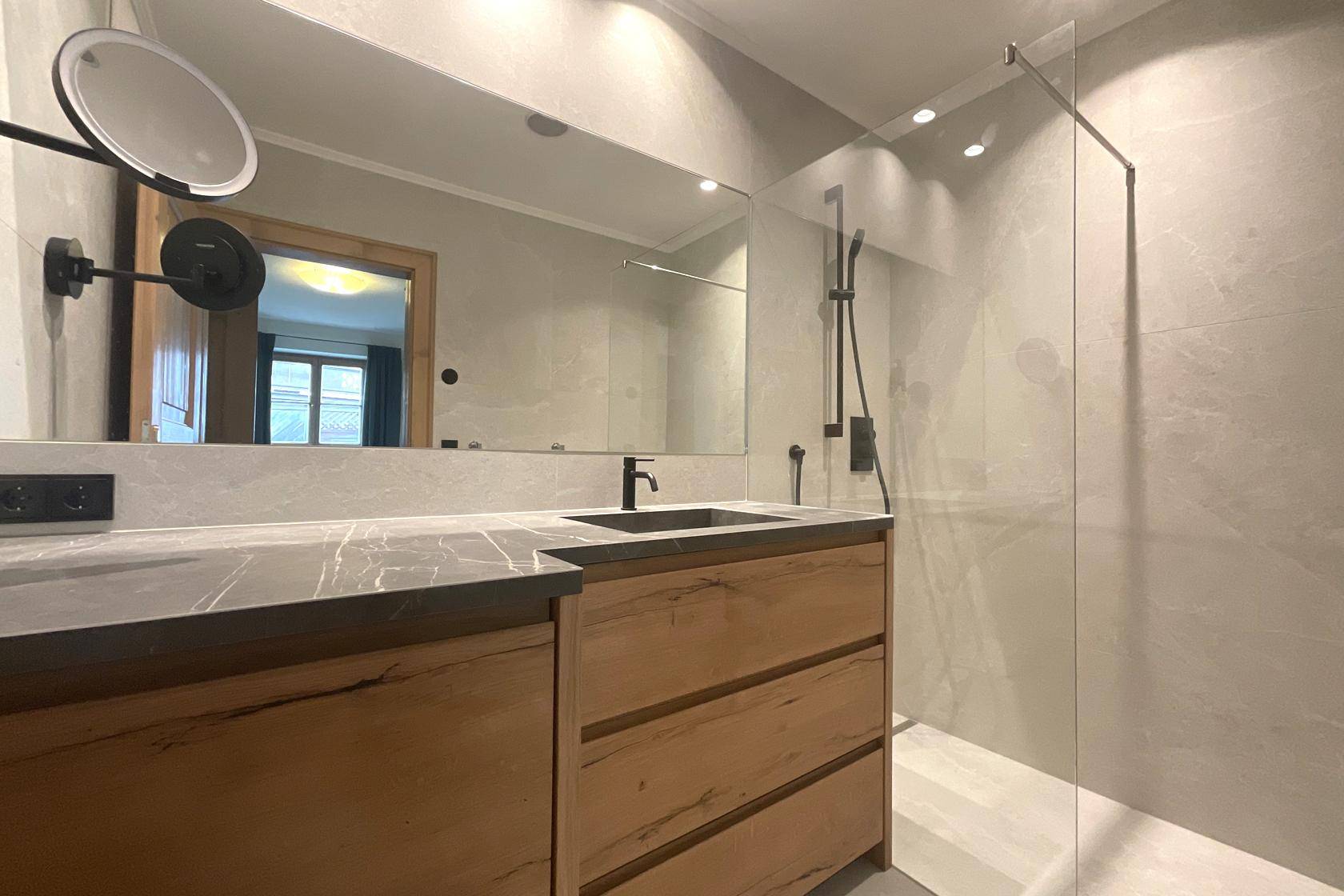 Modernes Badezimmer mit Doppelwaschbecken, Holzunterschrank und großer begehbarer Dusche.