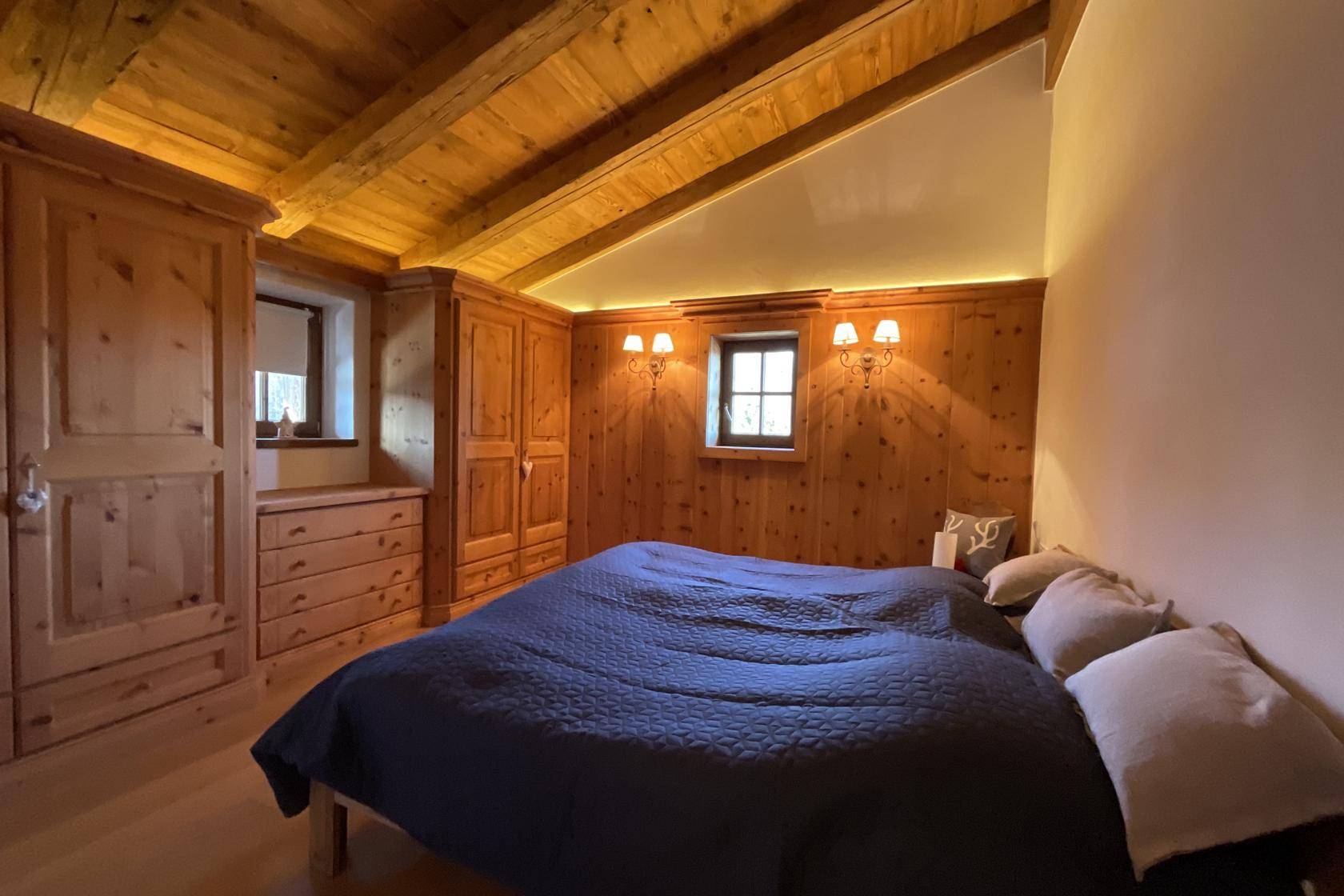 Schlafzimmer mit Holzbalkendecke, Doppelbett und Einbauschränken aus Holz.