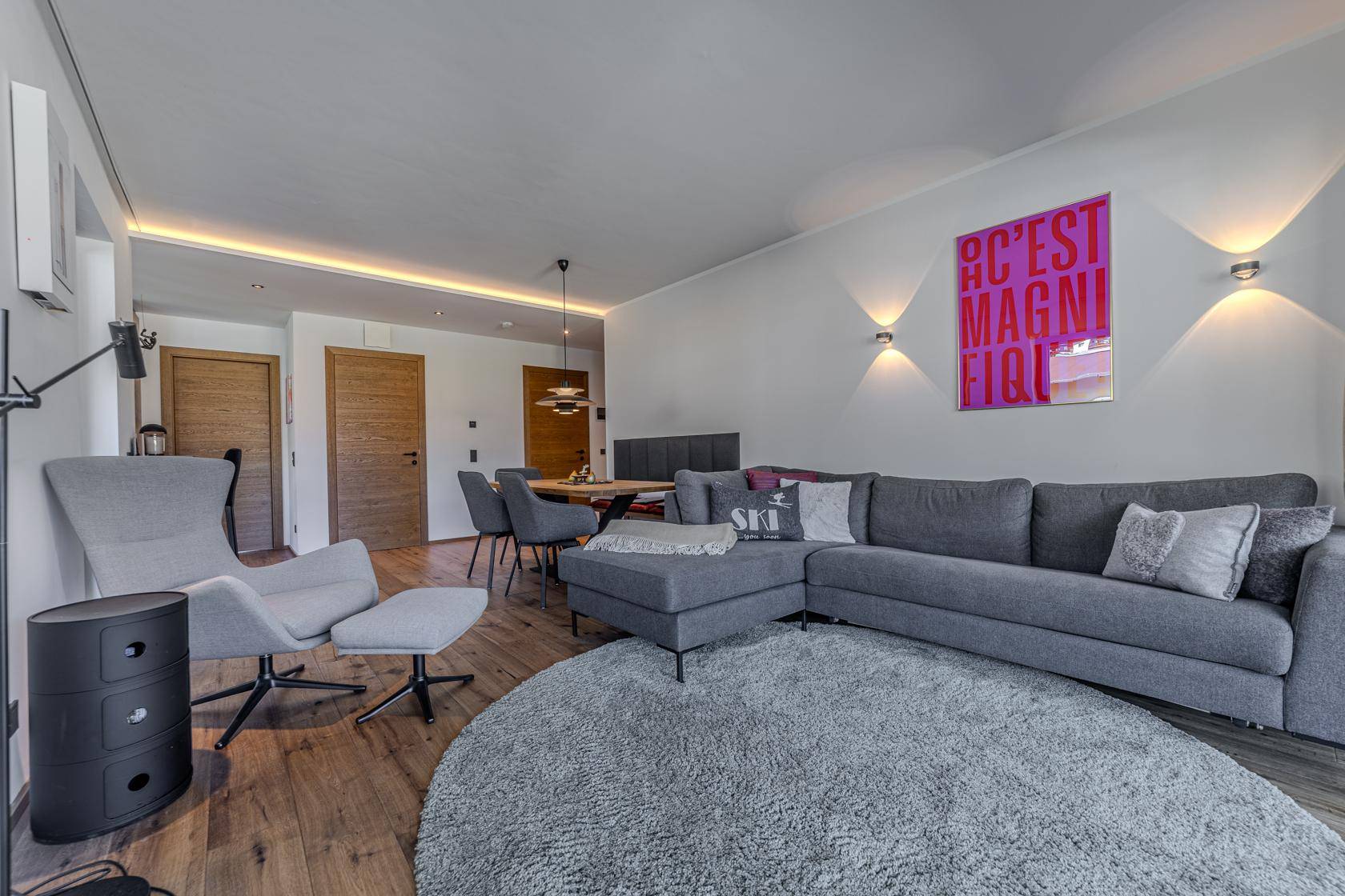 Moderner Wohnbereich mit grauem Sofa, Holzboden und farbenfroher Kunst an der Wand.