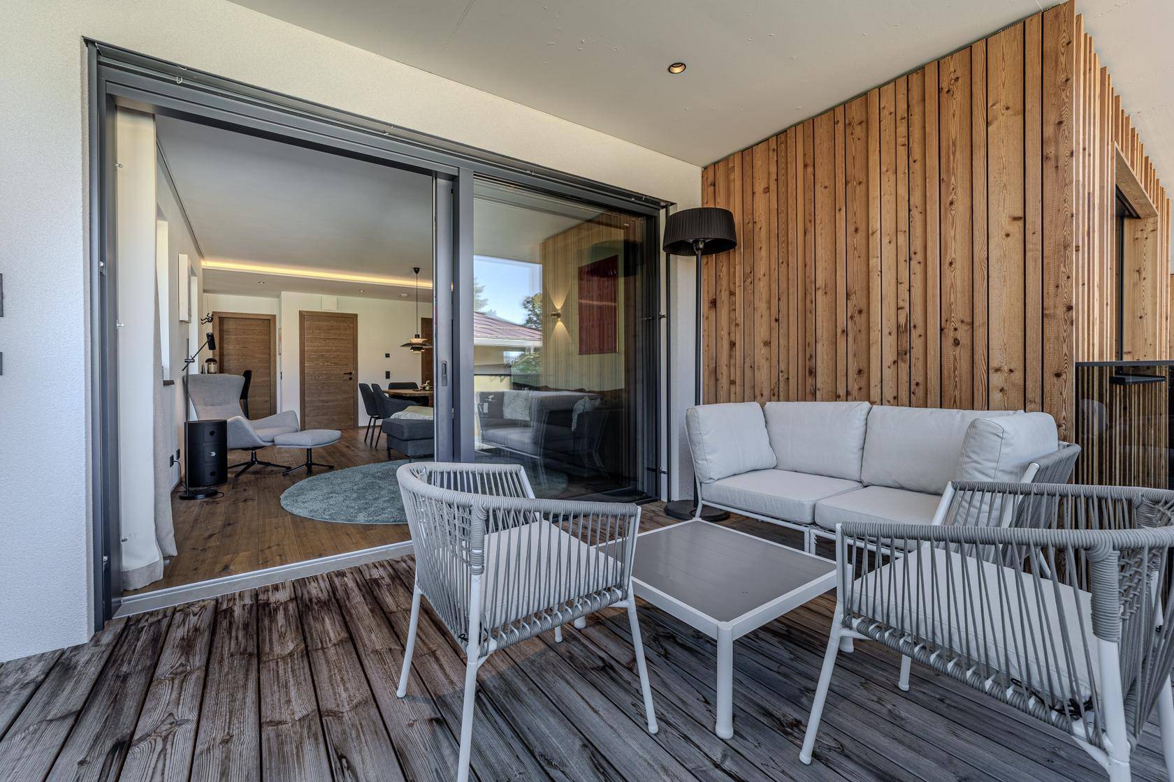 Geräumiger Balkon mit Holzdeck und bequemen Outdoor-Möbeln, direkt vom Wohnbereich zugänglich.