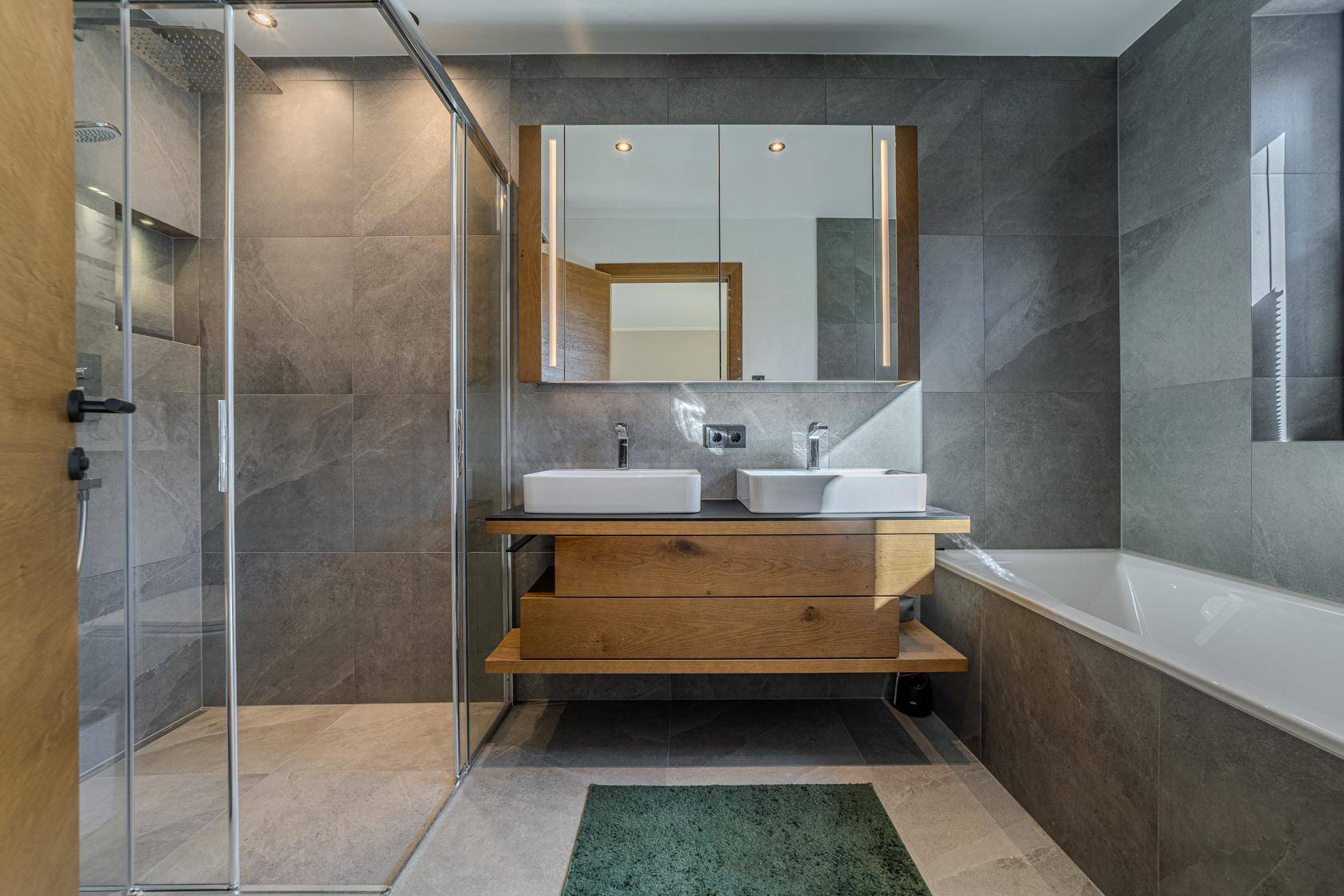 Modernes Badezimmer mit großformatigen Fliesen, Doppelwaschbecken, begehbarer Dusche und Badewanne.