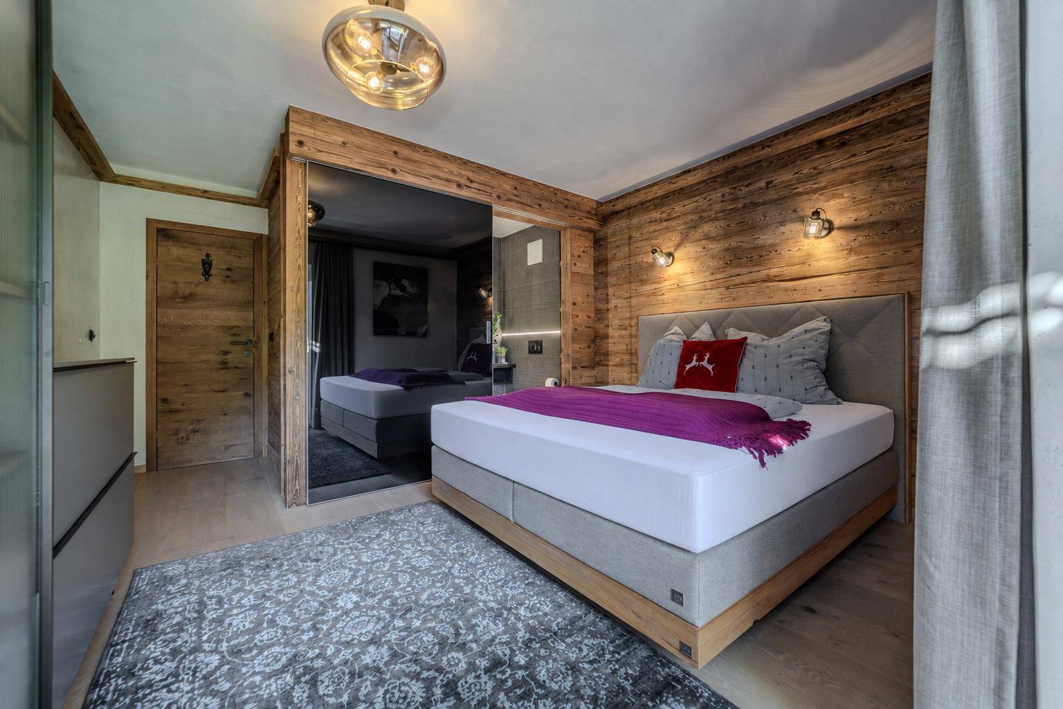 Gemütliches Schlafzimmer mit Holzwand, großem Bett und integriertem Spiegelschrank.