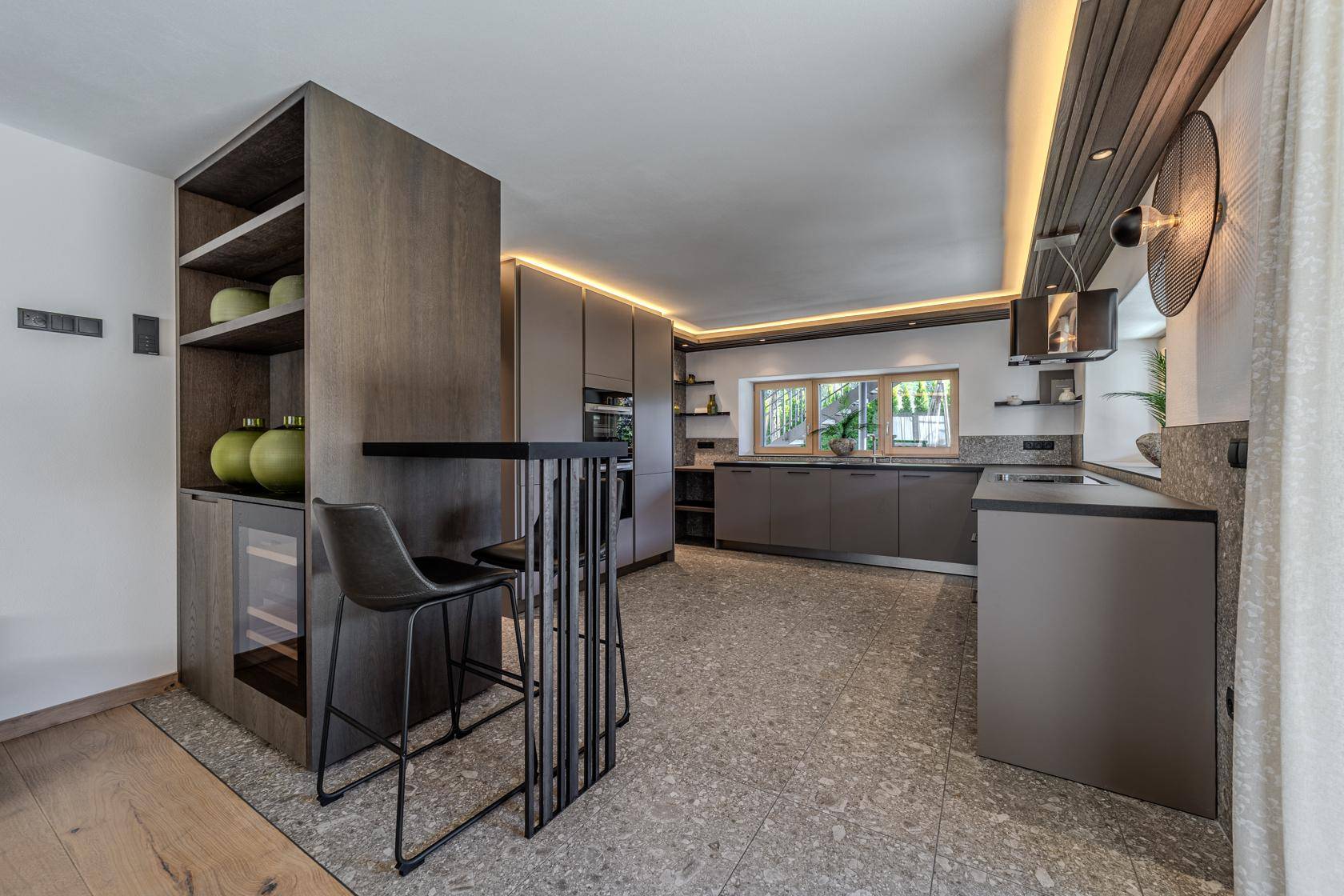 Moderne Küche mit dunklen Schränken, integriertem Weinkühler und Frühstücksbar.