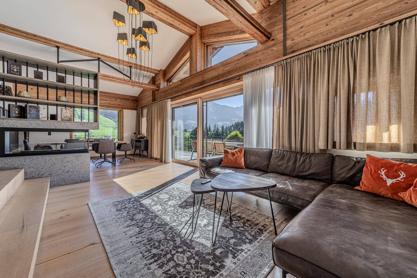 Gemütliches Wohnzimmer mit Ledersofa, Kamin und Zugang zur Terrasse mit Bergblick.
