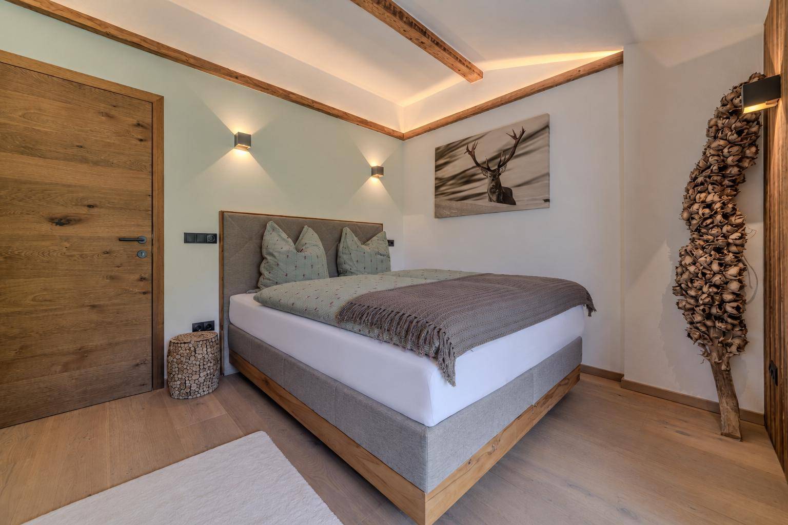Ruhiges Schlafzimmer mit Holztür, bequemen Bett und indirekter Beleuchtung.