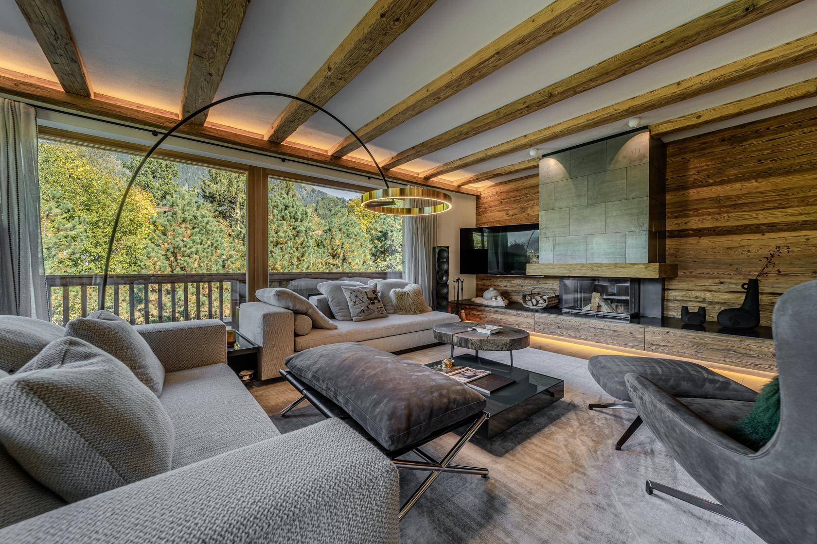 Gemütliches Wohnzimmer mit Kamin, Holzwänden und Panoramablick auf die Berge.