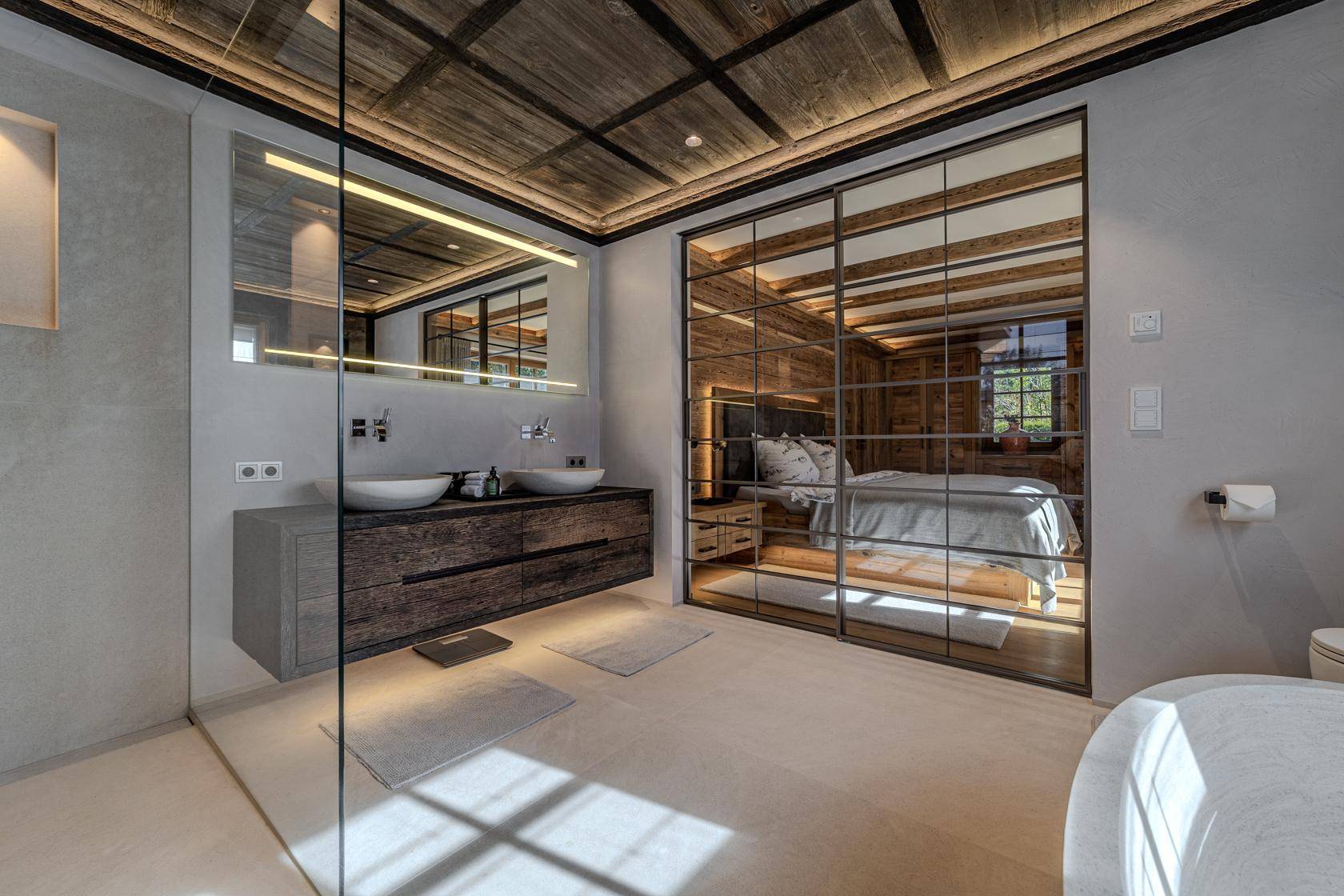 Luxuriöses Badezimmer mit Doppelwaschbecken, begehbarer Dusche und Blick ins Schlafzimmer.