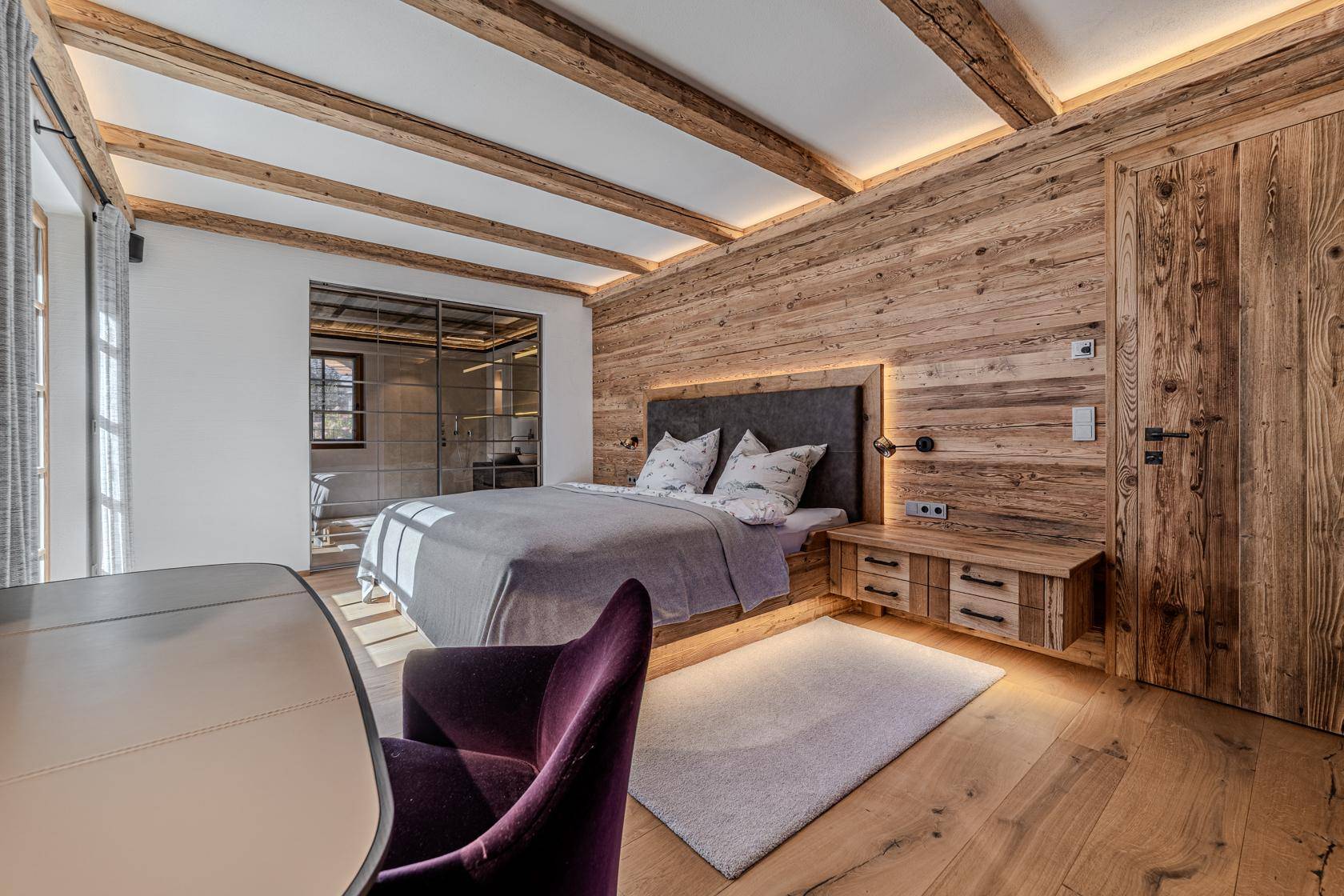 Schlafzimmer im alpinen Stil mit Holzwänden, Holzbalkendecke und integrierten Nachttischen.
