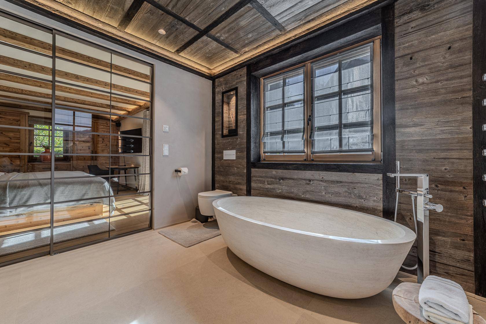 Elegantes Badezimmer mit freistehender Badewanne, WC und Holzwänden.