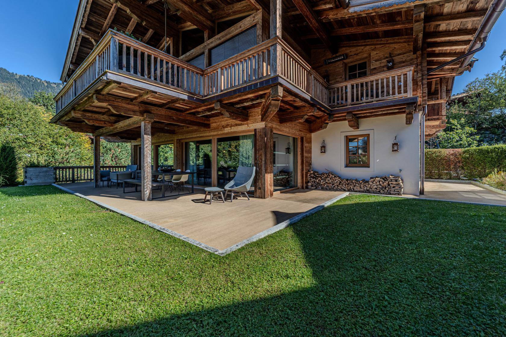 Traditionelles Holzchalet mit großer Terrasse, Garten und Balkonen.