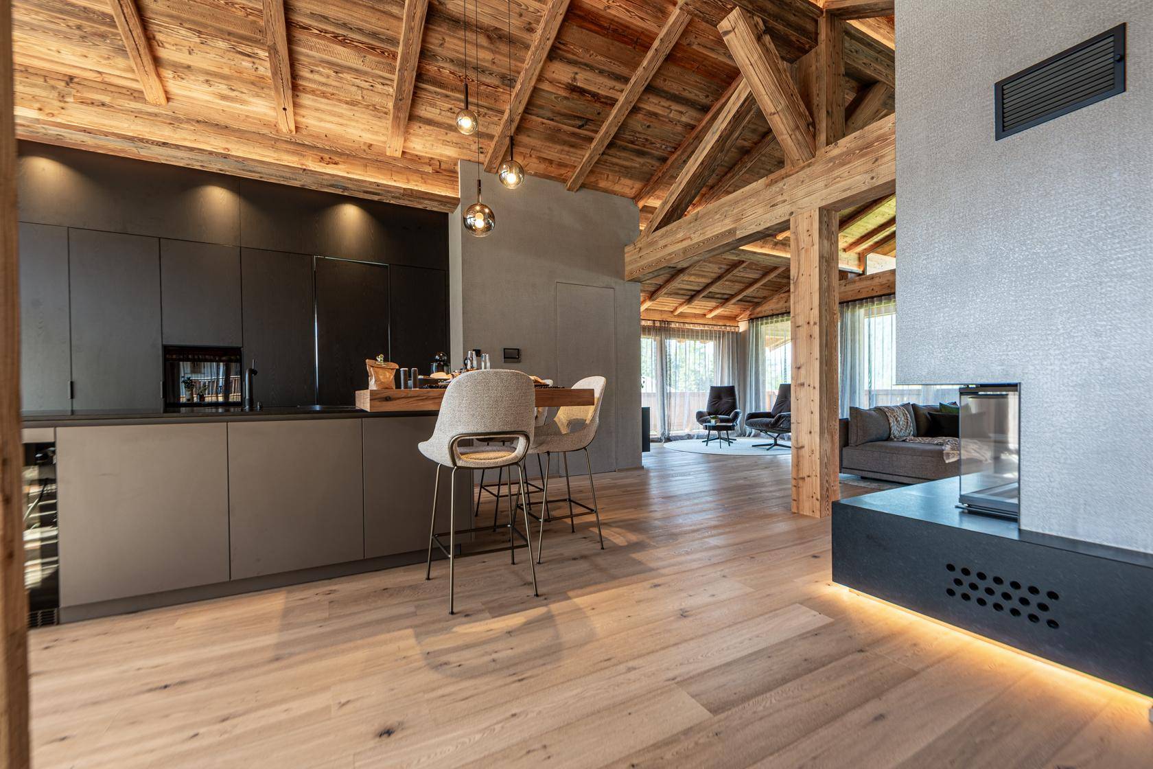 Moderne offene Küche mit dunklen Schränken, Frühstücksbar und Holzbalkendecke.