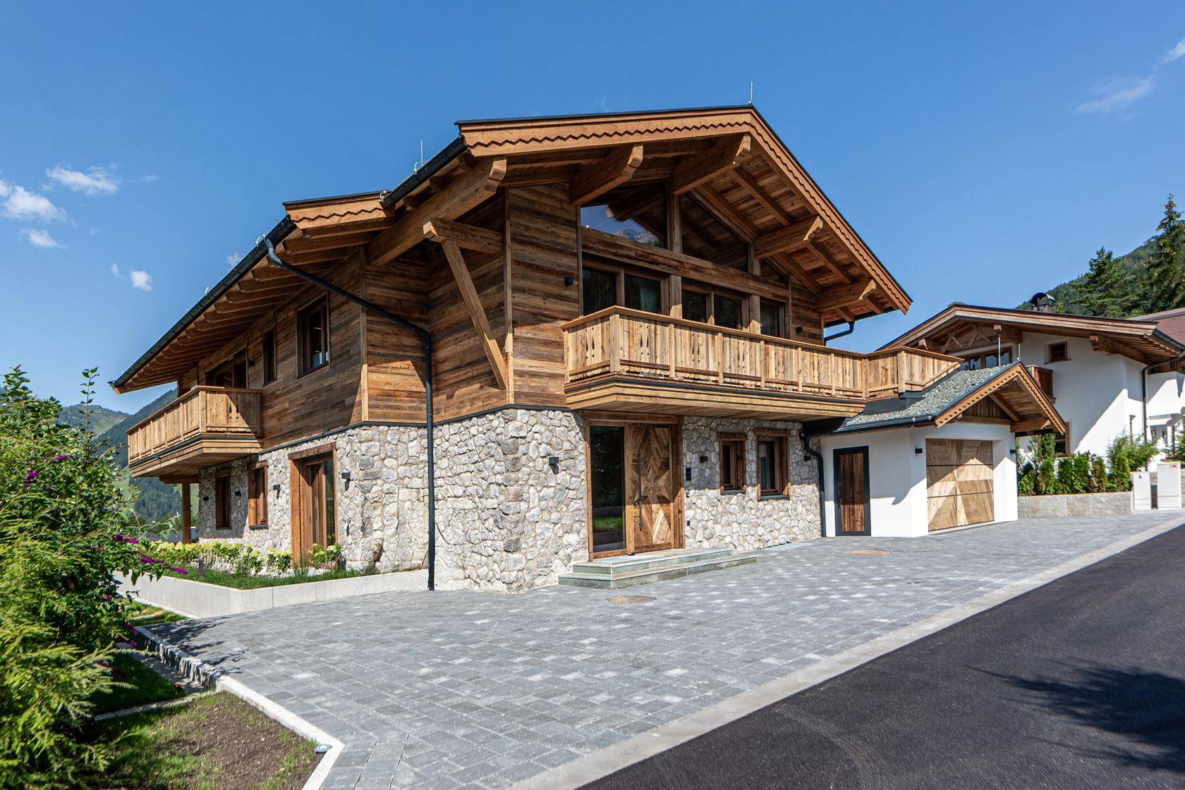 Traditionelles Holzhaus mit Steinfassade und mehreren Balkonen in alpiner Umgebung.