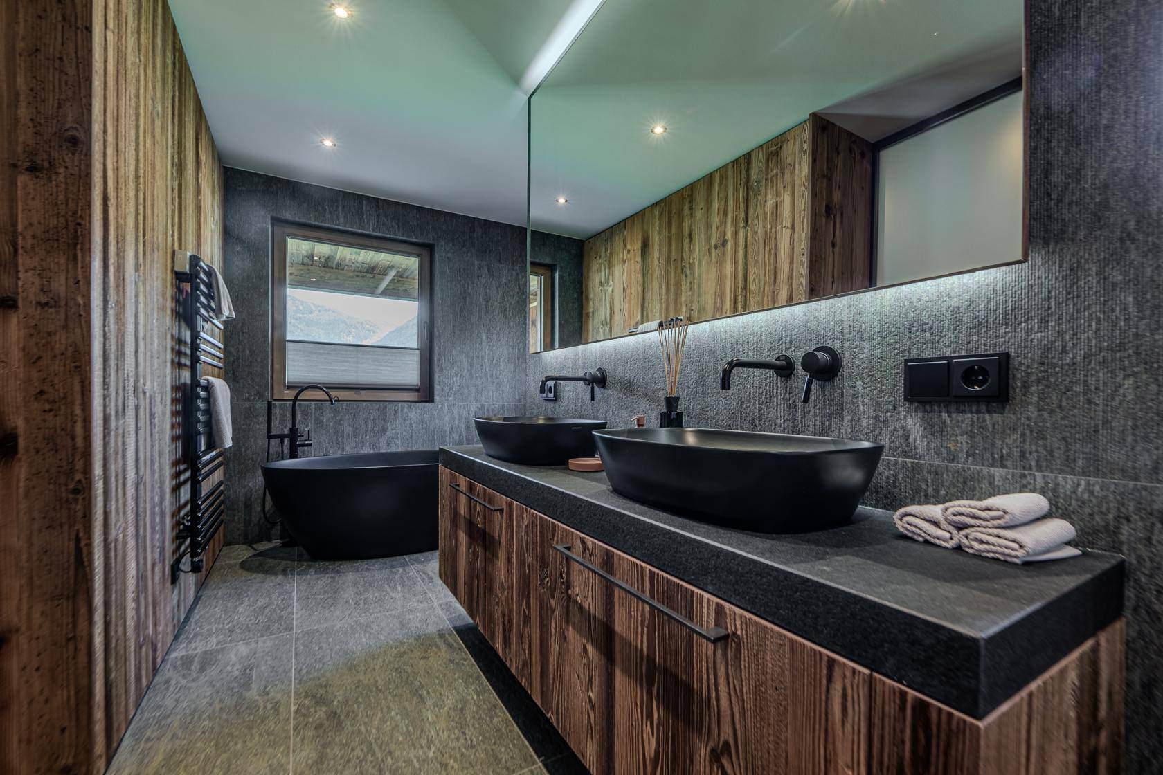 Modernes Badezimmer mit Doppelwaschbecken, freistehender Badewanne und Holzakzenten.