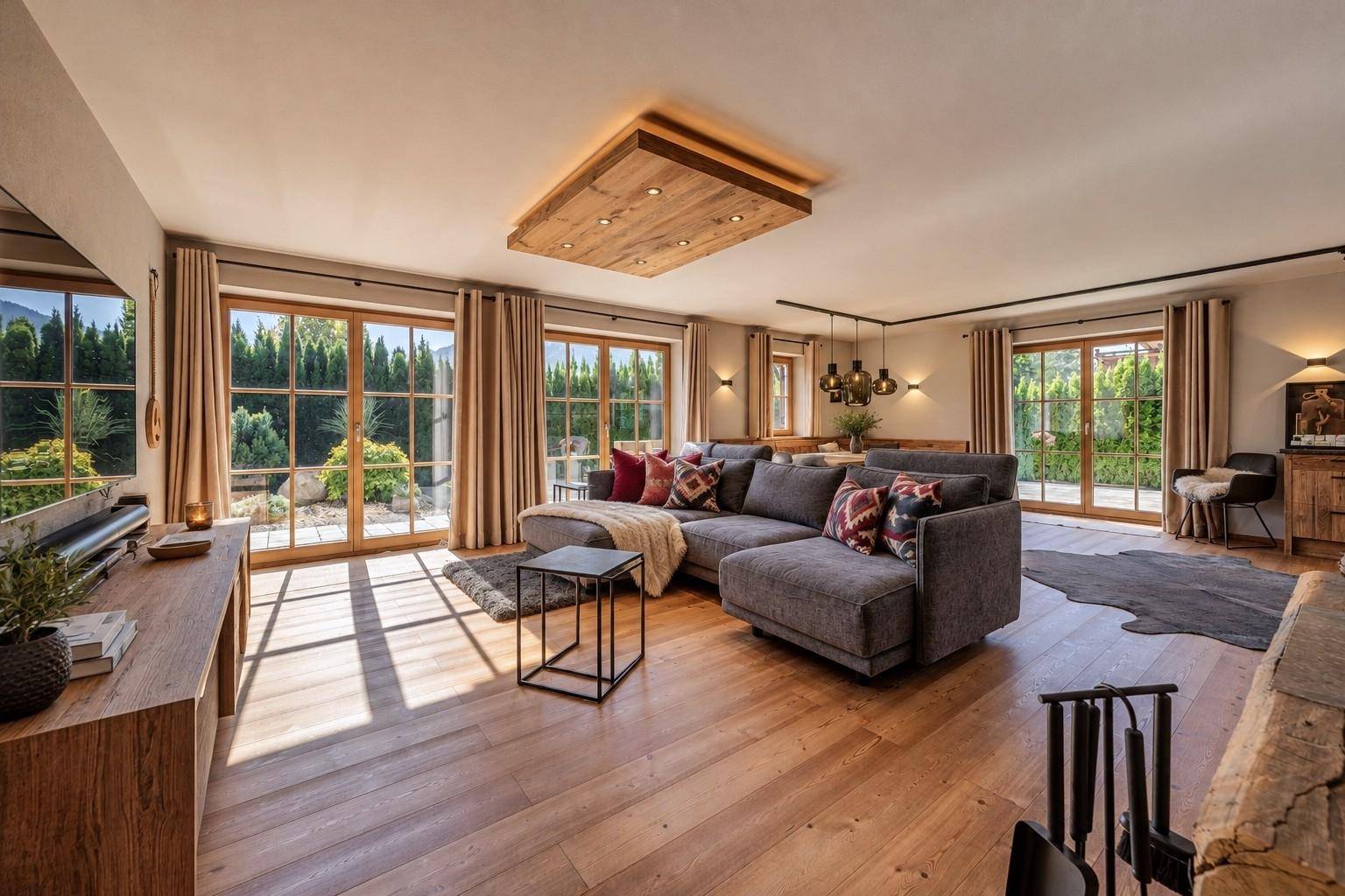 Helles und geräumiges Wohnzimmer mit Holzboden, großem Sofa und Zugang zur Terrasse mit Gartenblick.