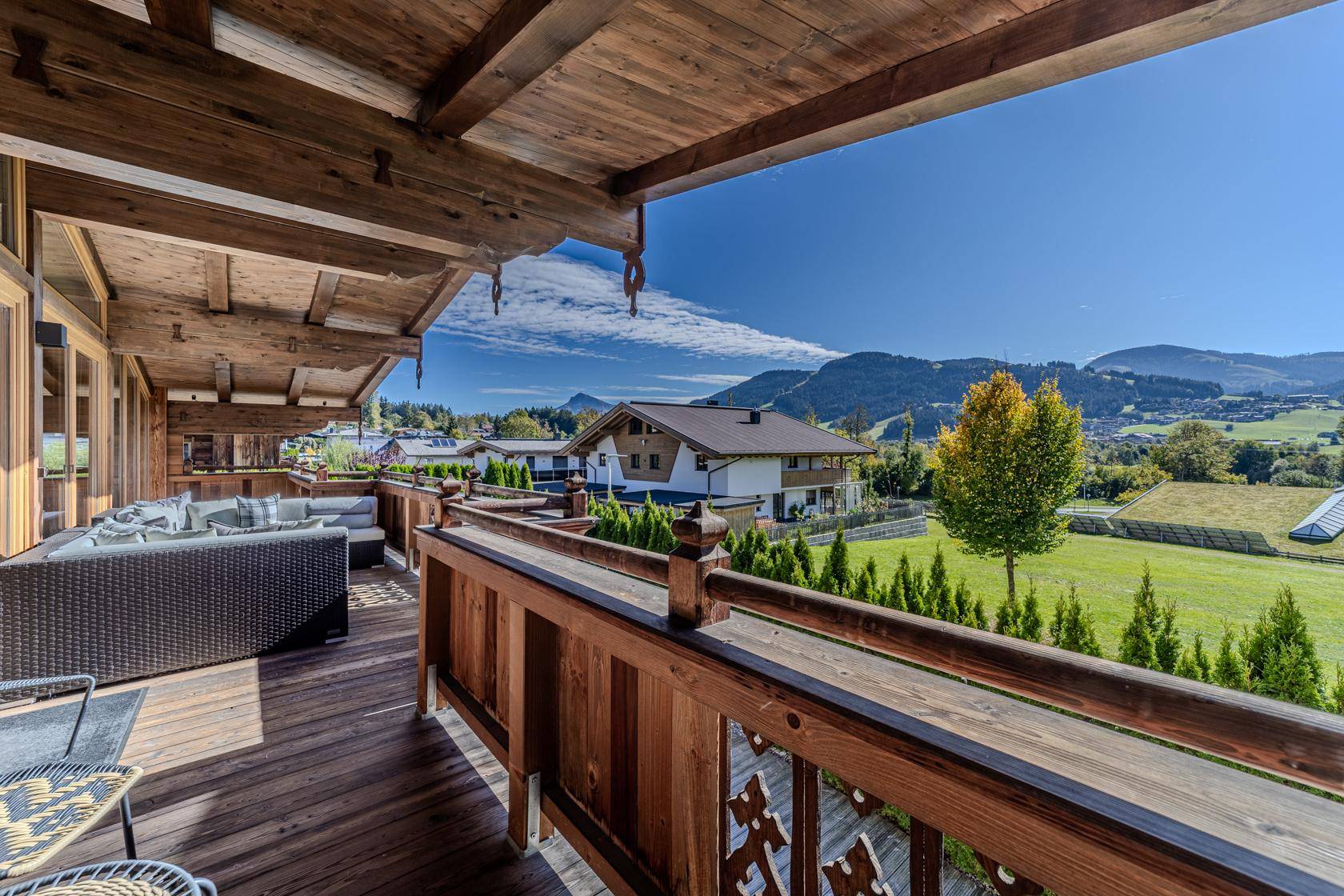 Großer Holzbalkon mit bequemen Loungemöbeln und weitem Blick auf die umliegende Berglandschaft.